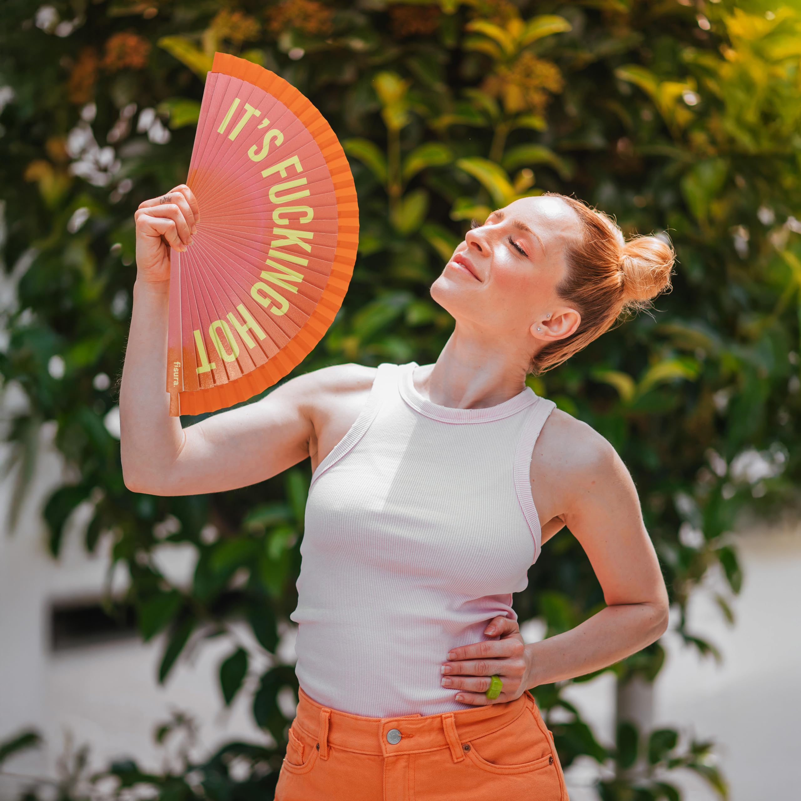 Fisura – Wachlarz ręczny z napisem "it’s f*cking hot”. Dwustronny model z drewna, różowo-pomarańczowy gradient. Kolorowy i praktyczny. Zawieszka. Wymiary: 42,5 x 23 cm