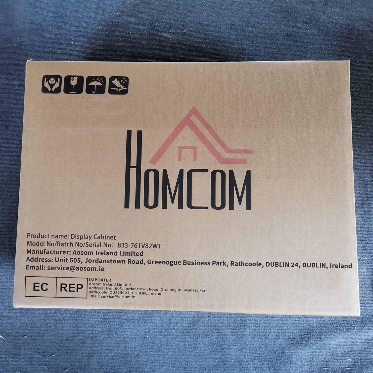 Packaging box for HOMCOM display cabinet showing brand logo and model number.