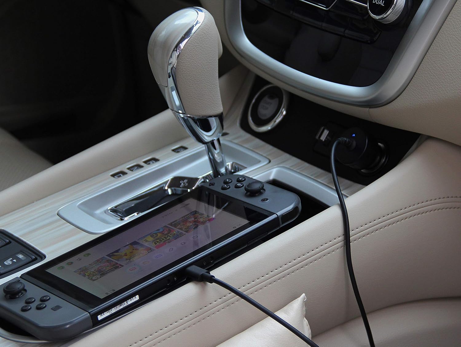 Nintendo Switch charging in a car's center console using the Amazon Basics Car DC Charger.