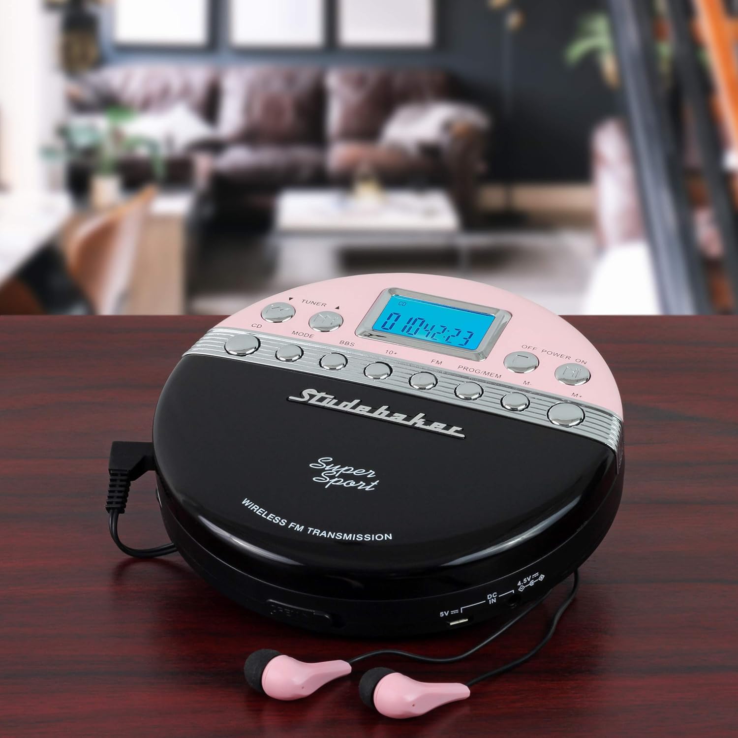 Studebaker SB3705PB Portable CD Player with pink earbuds connected, resting on a wooden table.