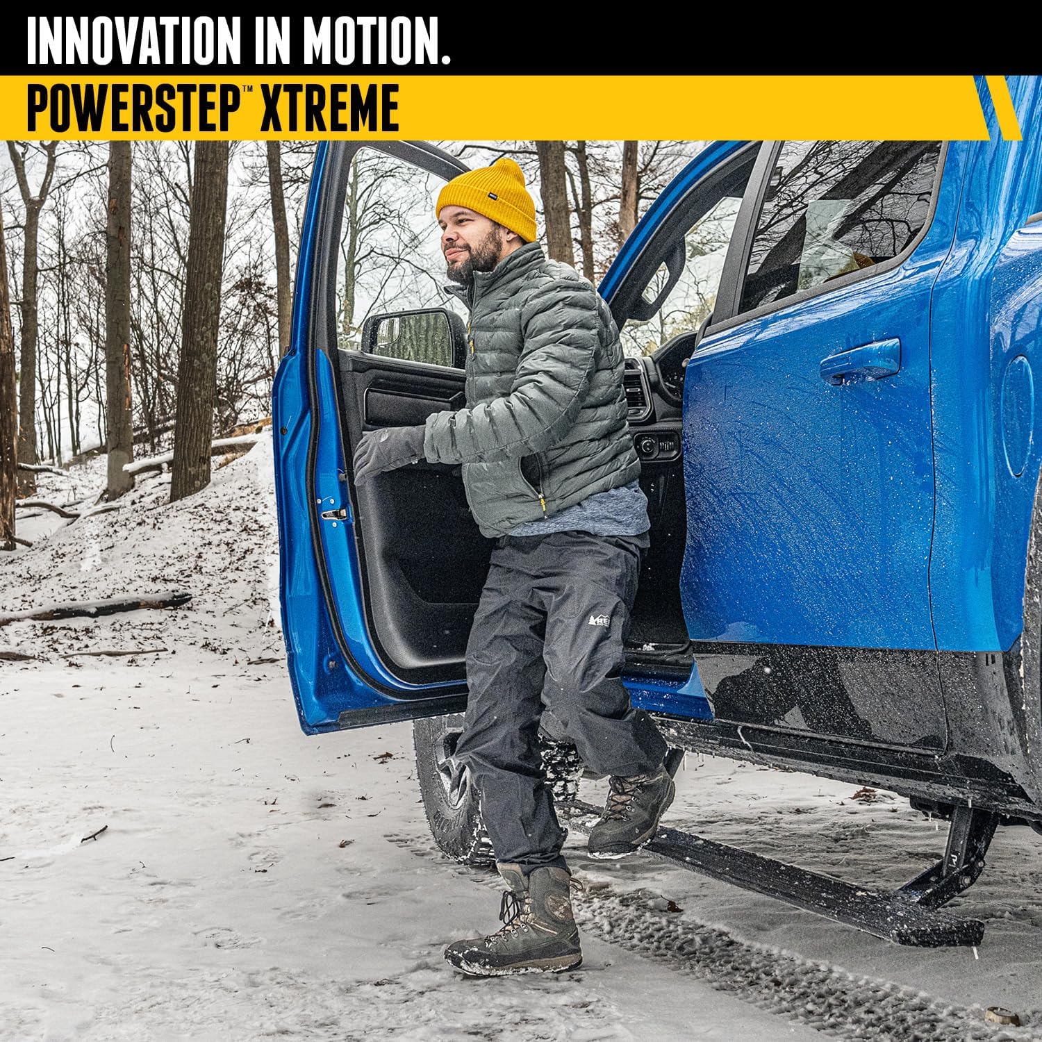 A person stepping onto a deployed AMP Research PowerStepXTreme from a blue truck in a snowy environment.