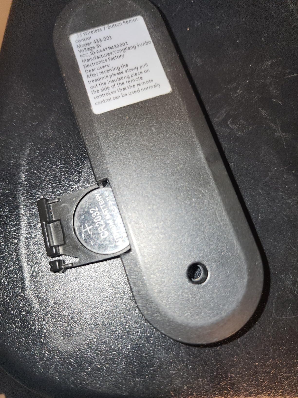 Close-up image showing the correct orientation for battery insertion into the remote control, with the flat side facing the back of the remote.