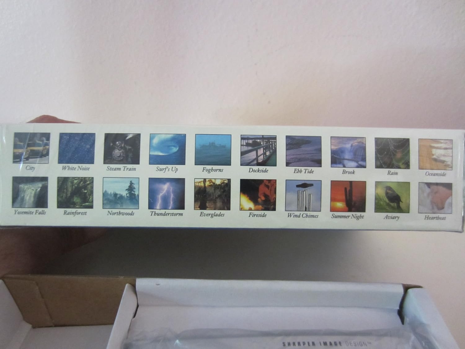 Side of the Sharper Image Travel Sound Soother 20 box displaying 20 different sound environment icons and names.