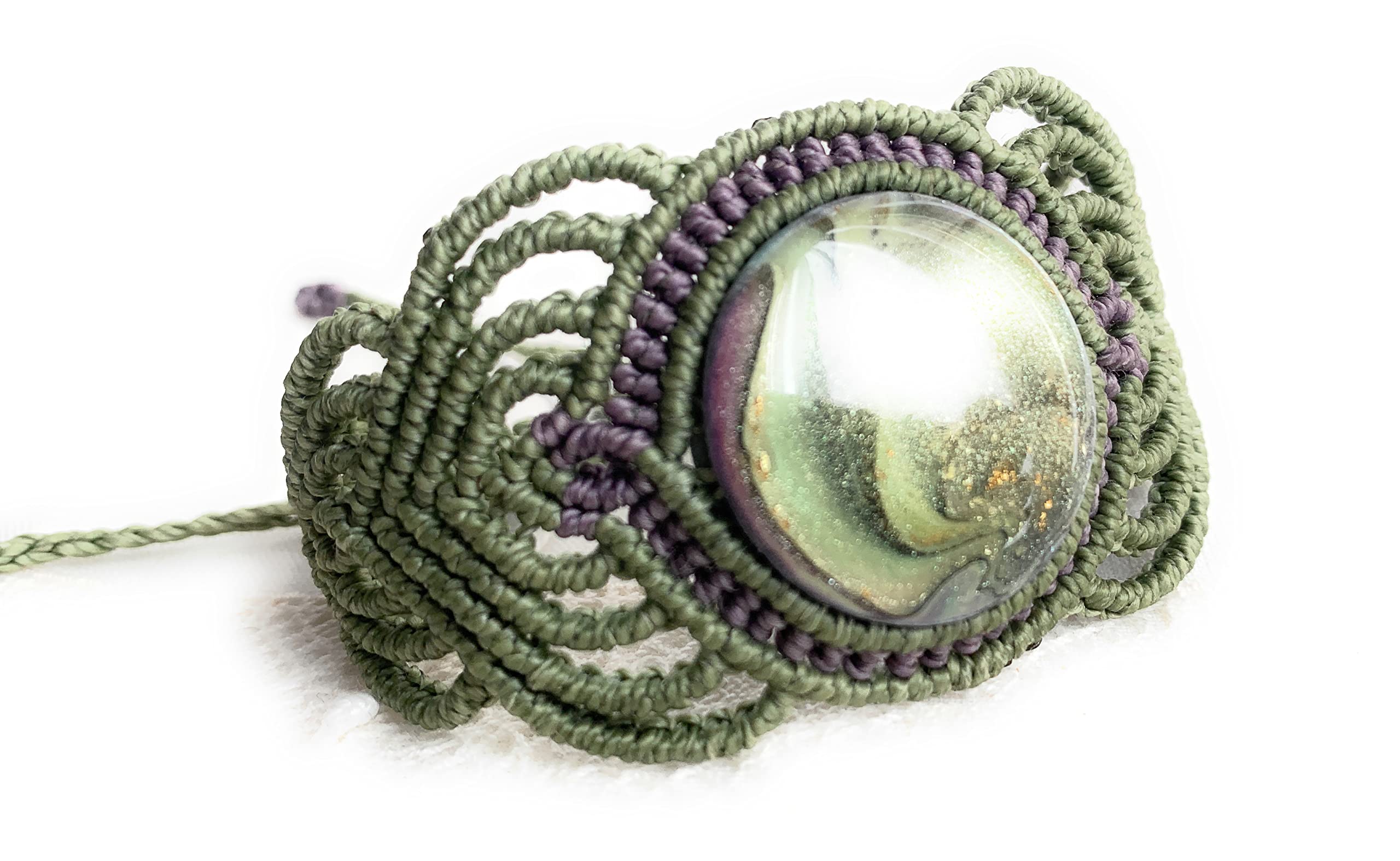 Brazalete,pulsera macramé hecho a mano con hilo encerado verde y lila y cabuchón engarzado de pasta polimérica también hecho a mano .Cierre ajustable