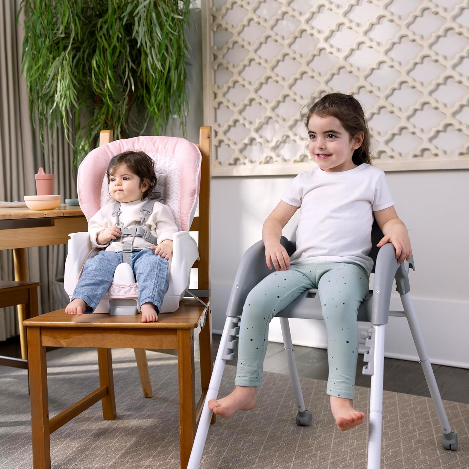 Two children, one in a booster seat on a dining chair and another in a toddler chair, demonstrating dual seating options.