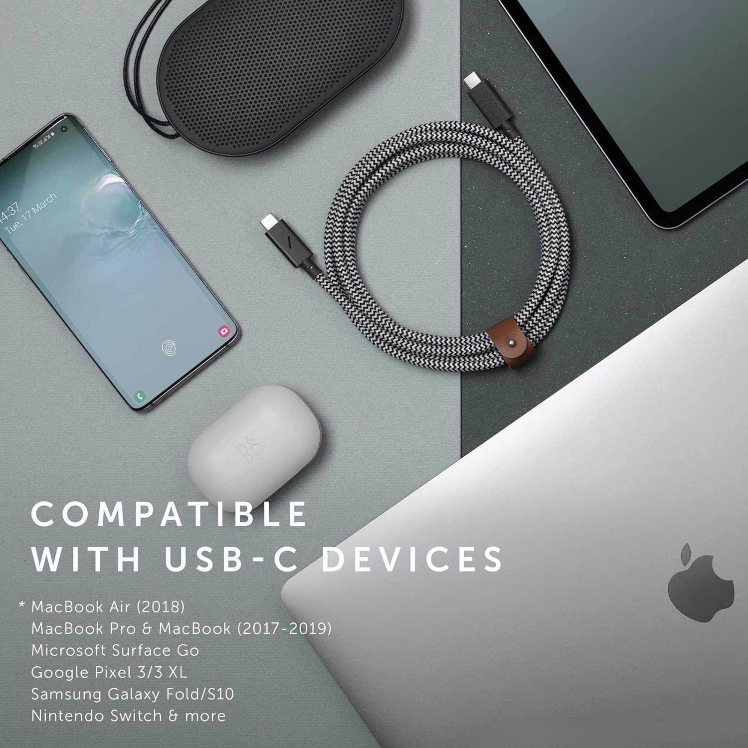 Overhead shot of the cable coiled on a desk with various compatible devices like a MacBook, smartphone, and tablet