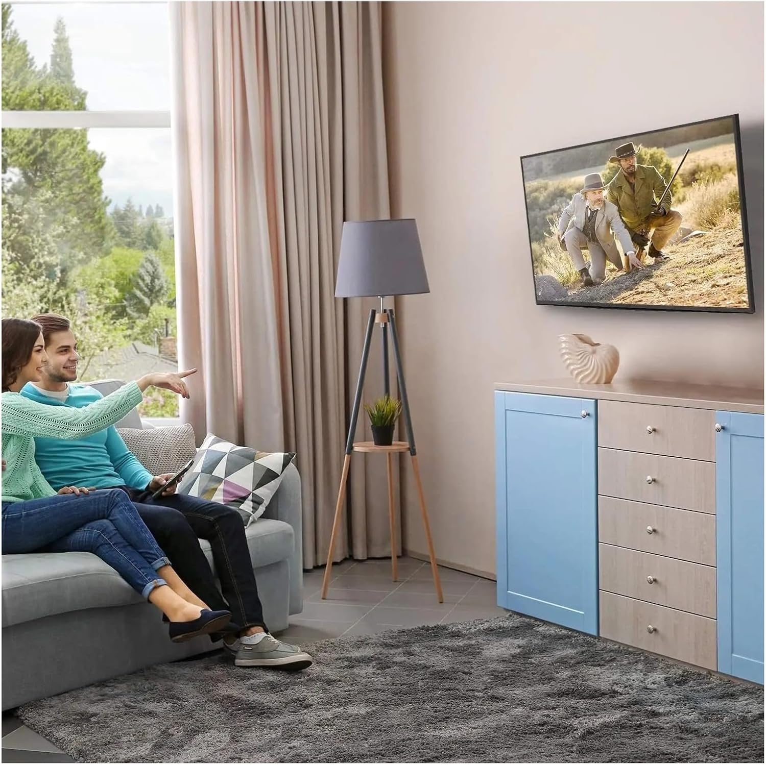 A couple comfortably watching a wall-mounted TV in a living room setting.