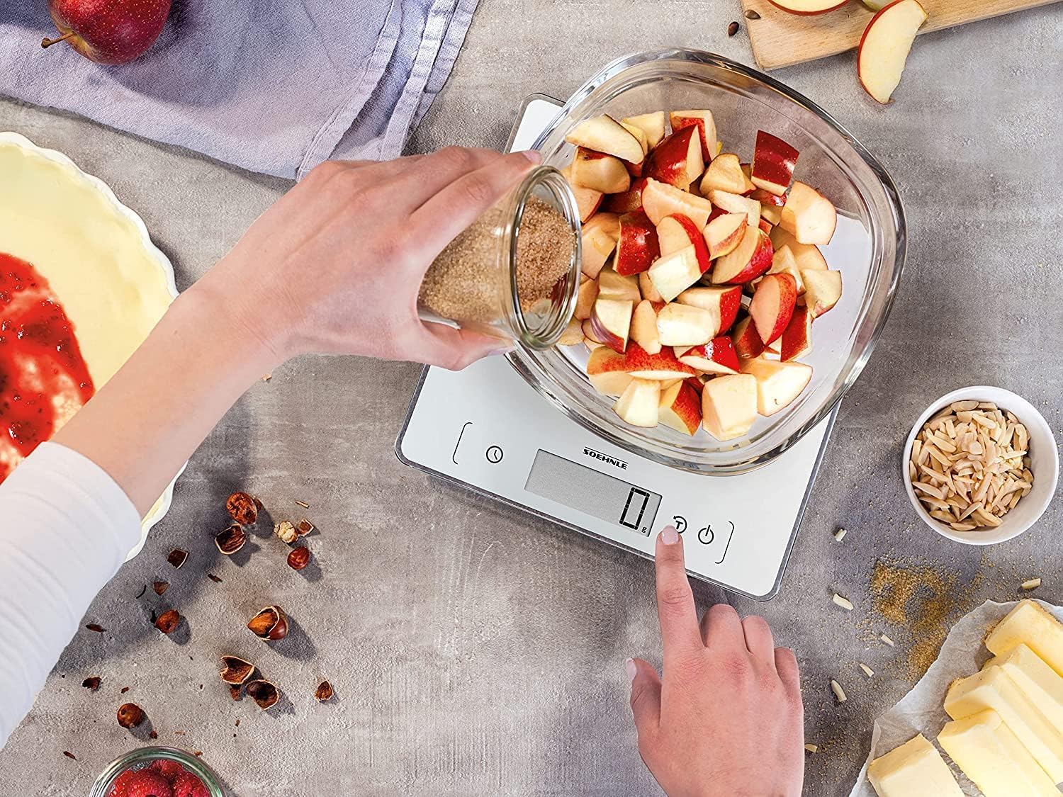 Hand using the tare function to weigh ingredients in a bowl