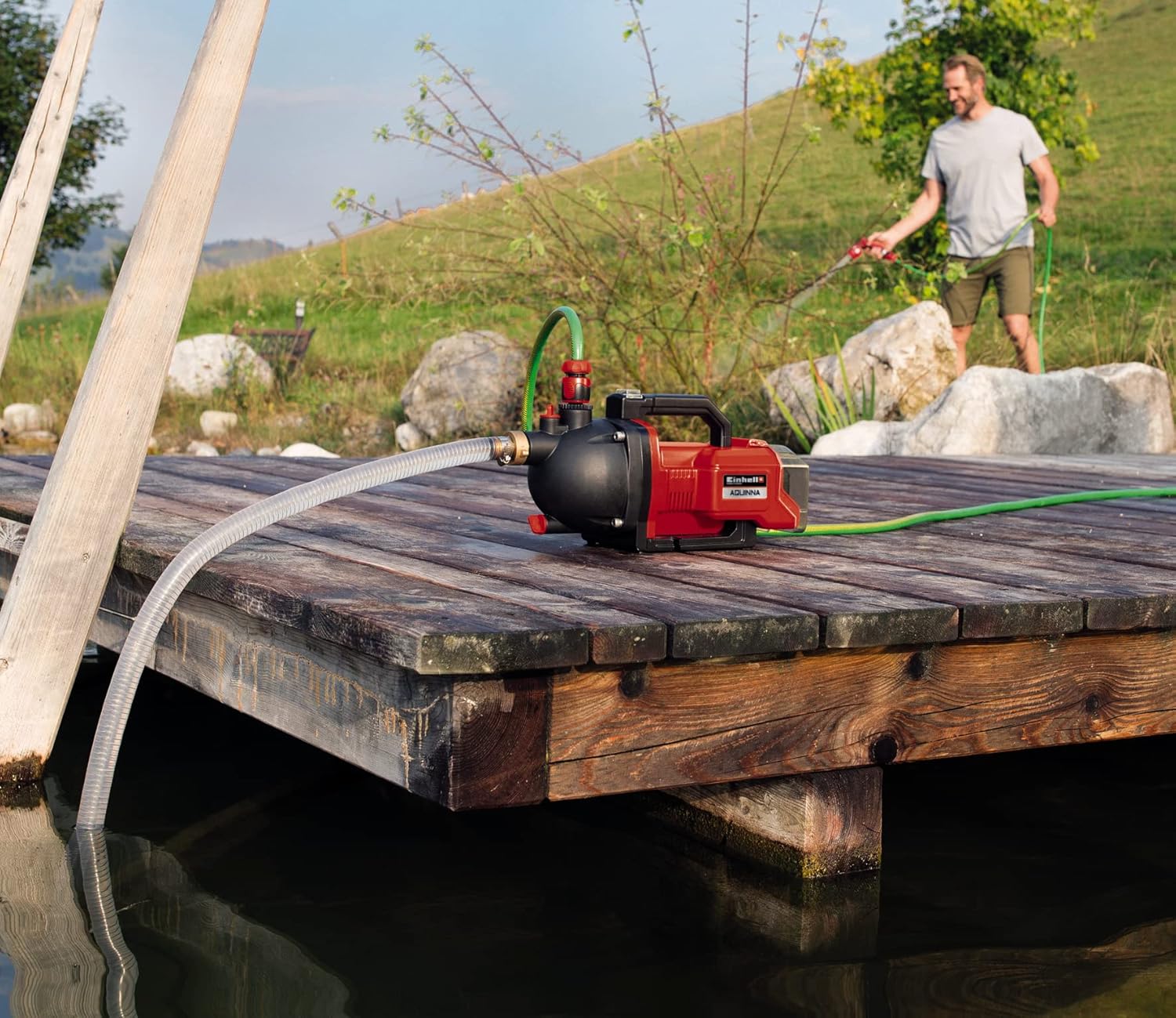 Man using the Einhell AQUINNA PX-C pump to water plants from a pond