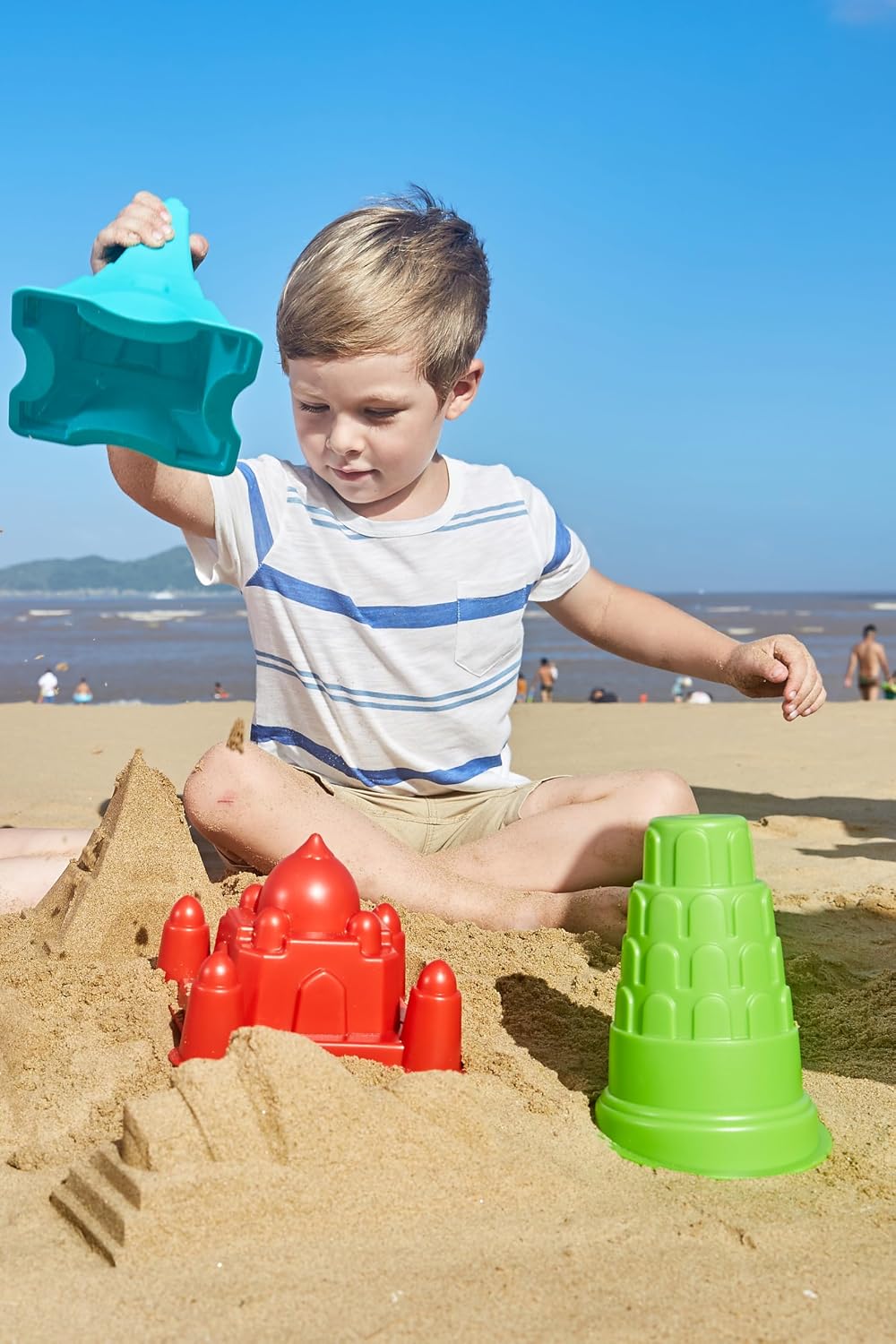 Child playing with Hape sand molds on a beach