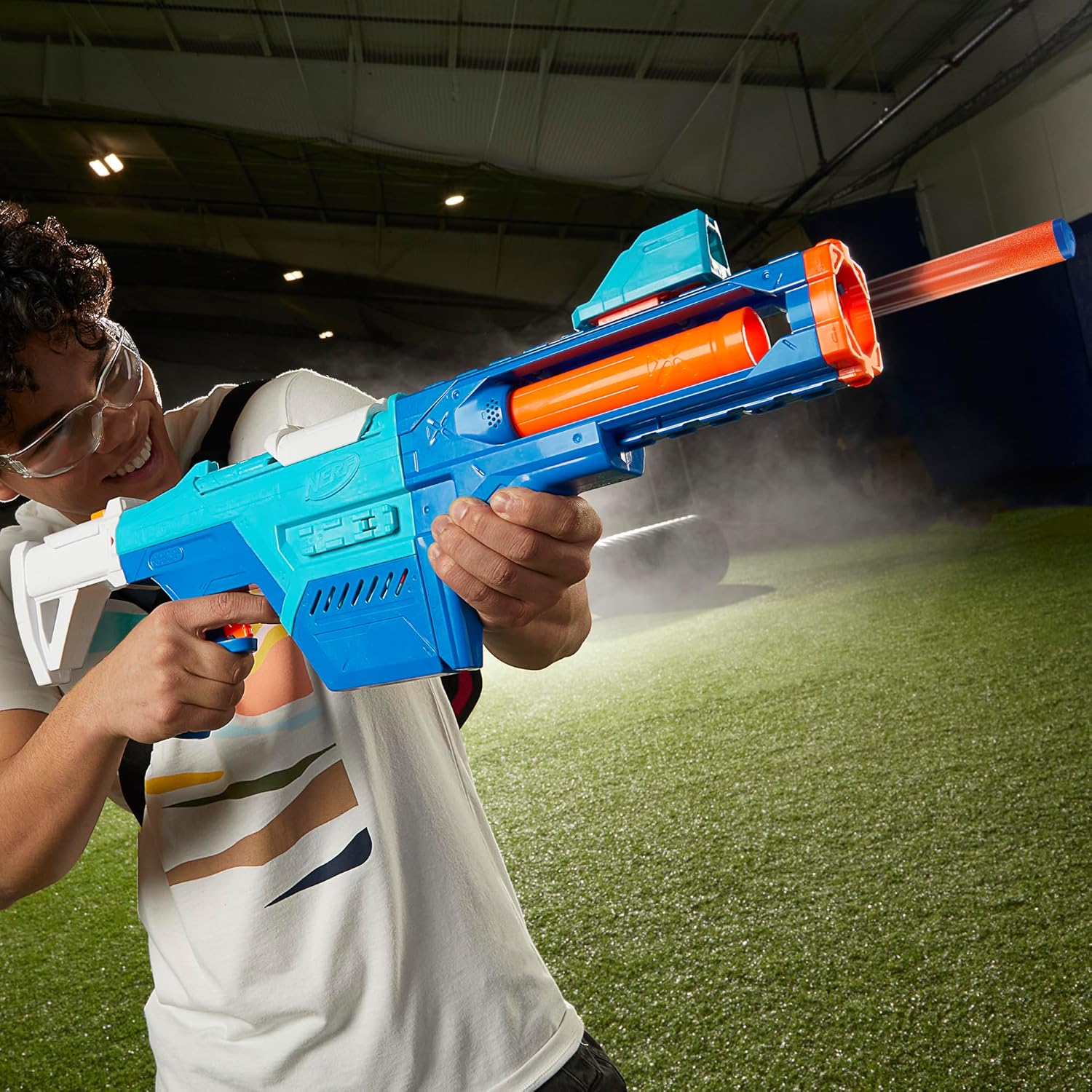 A person wearing safety glasses, holding and firing the fully assembled Nerf N Series Shadow Storm Blaster, with a dart visibly exiting the barrel.