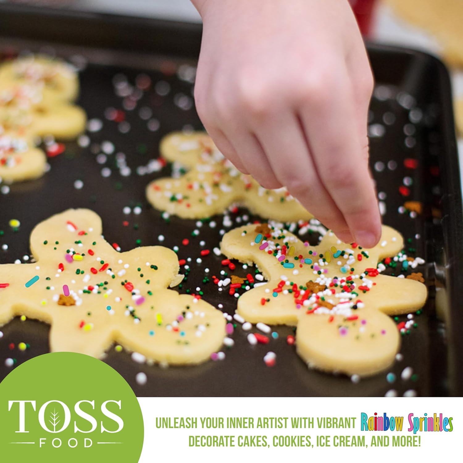 Child's hand sprinkling TOSS Rainbow Sprinkles onto gingerbread cookies.