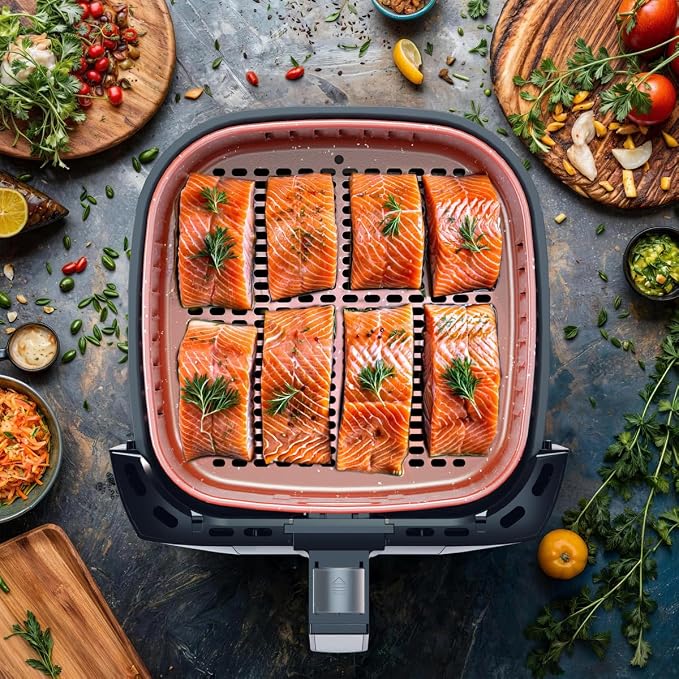 Visão aérea do cesto da Air Fryer Britânia com oito postas de salmão temperadas com alecrim prontas para assar.