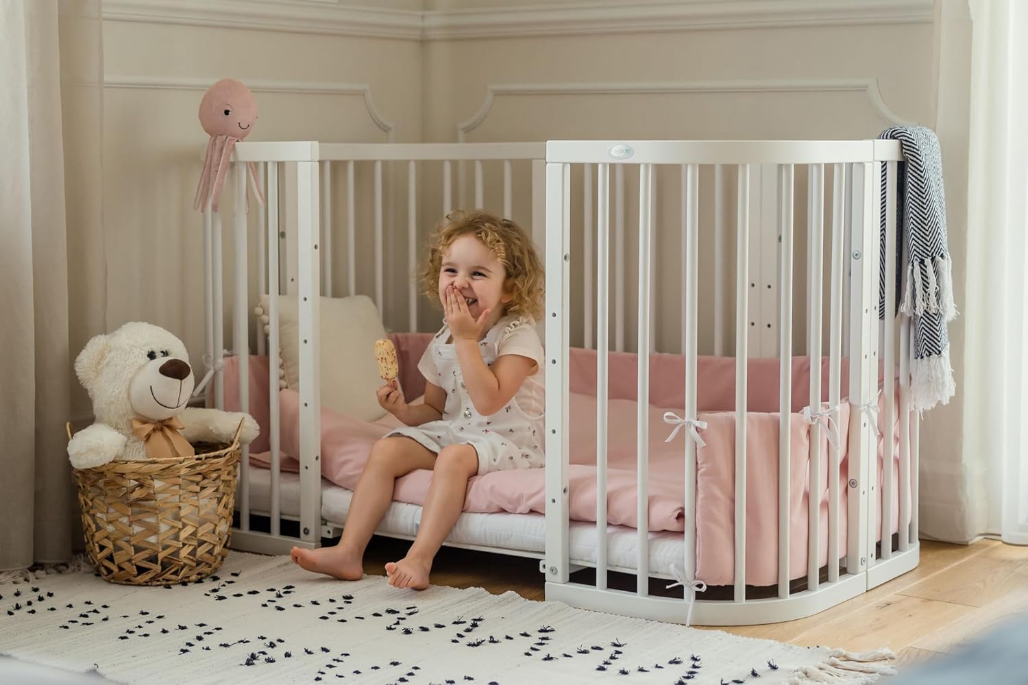 A child sitting comfortably inside the Waldin crib configured as a large bed.