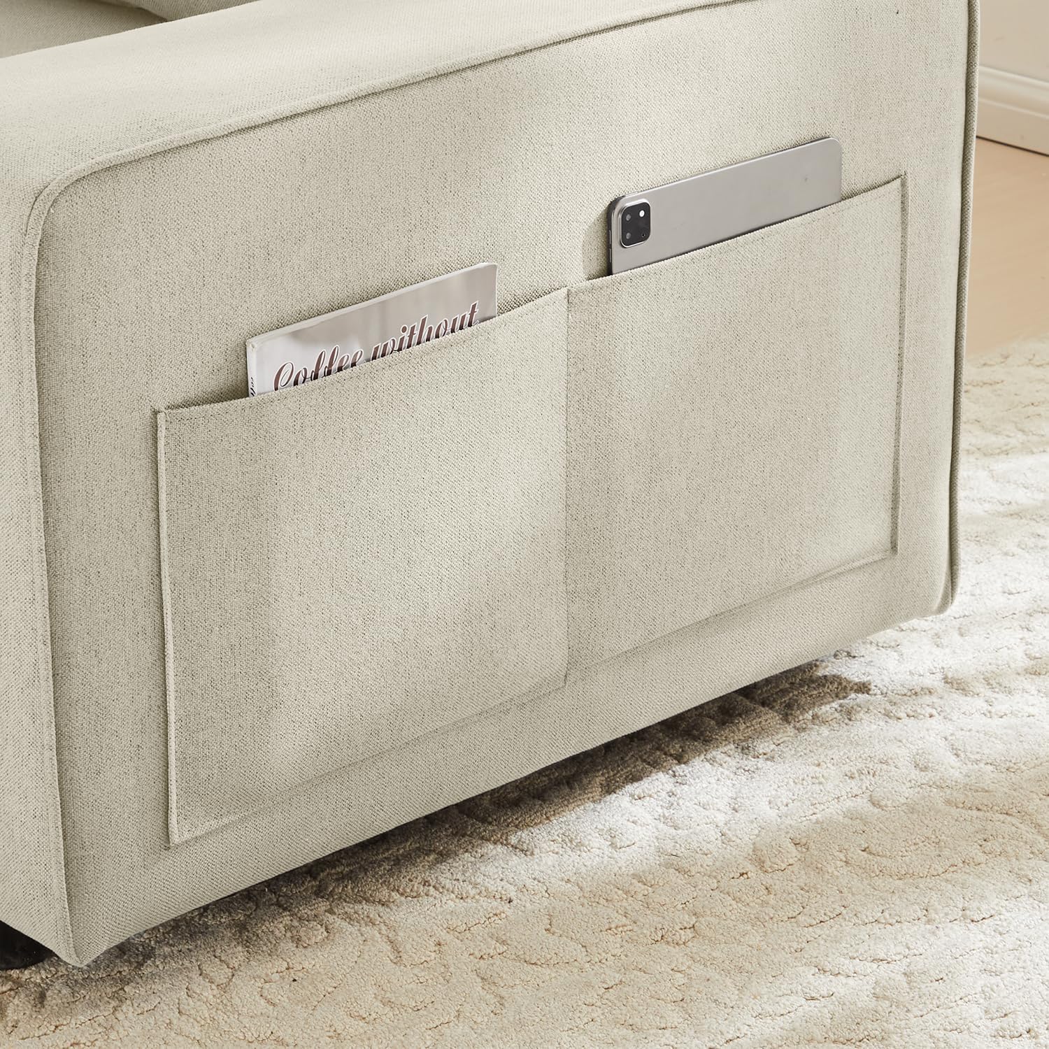 Close-up of the sofa armrest showing integrated side pockets holding a magazine and a tablet