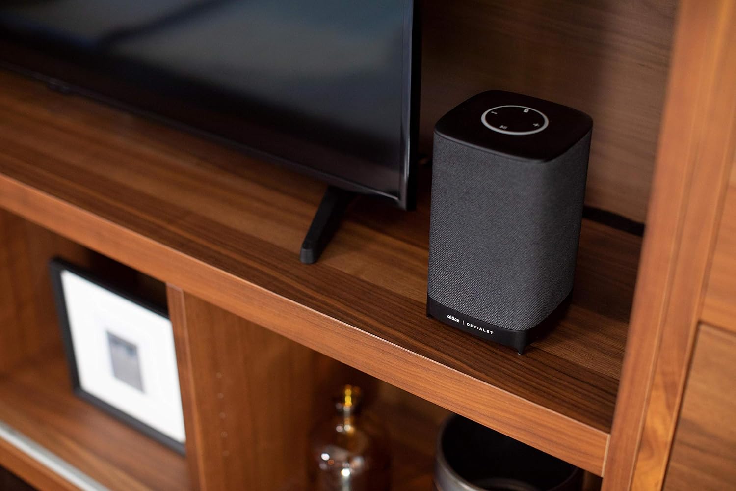 Altice Amplify Smart Speaker placed on a shelf next to a TV