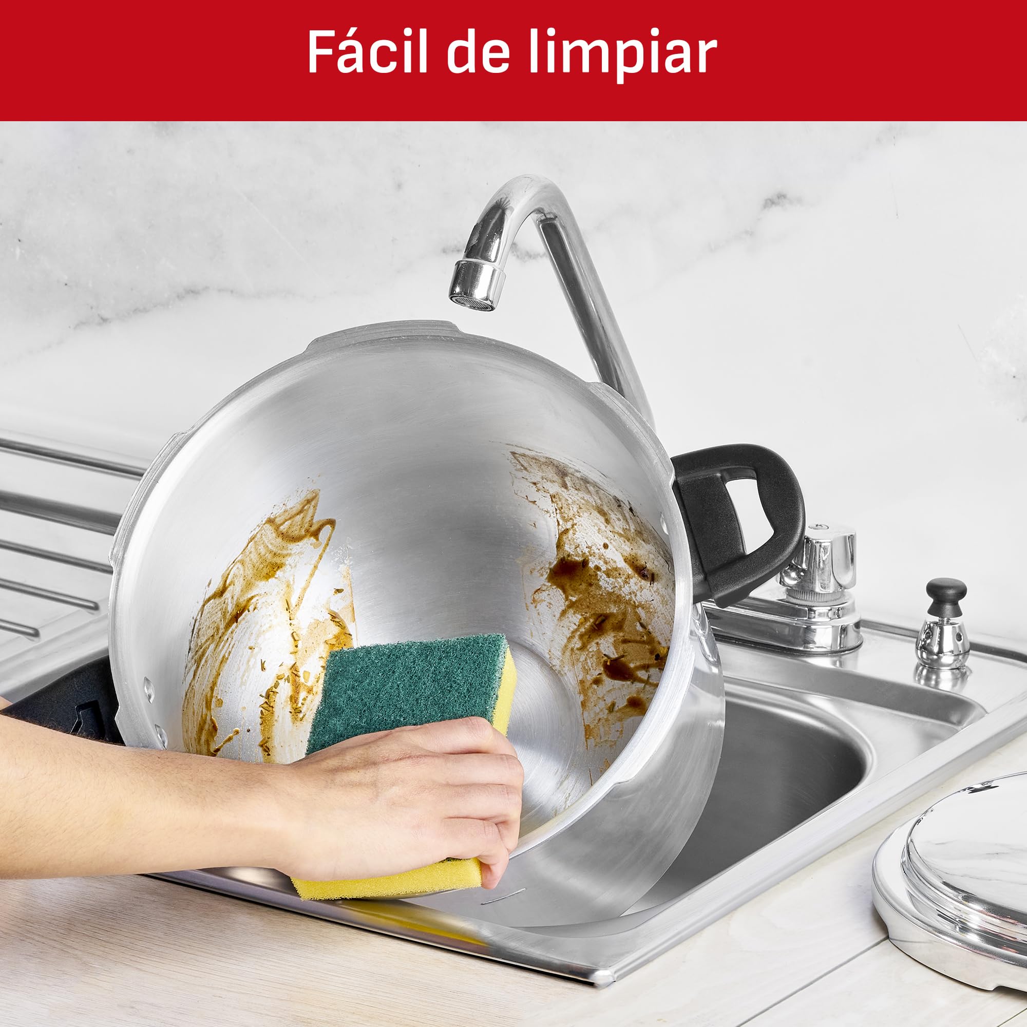 A hand cleaning the interior of the T-fal pressure cooker with a sponge under running water, demonstrating its easy-to-clean design.