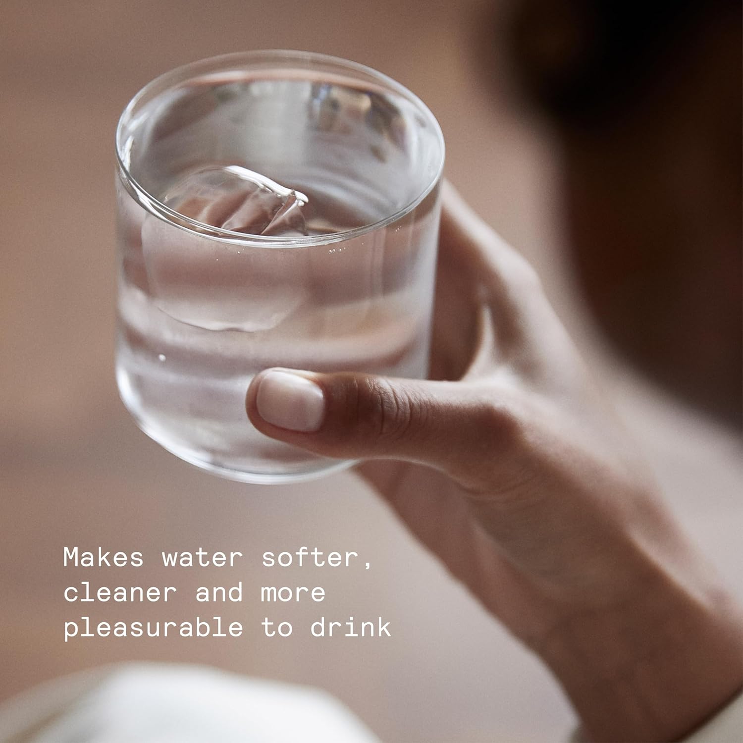 Hand holding a glass of clear, filtered water