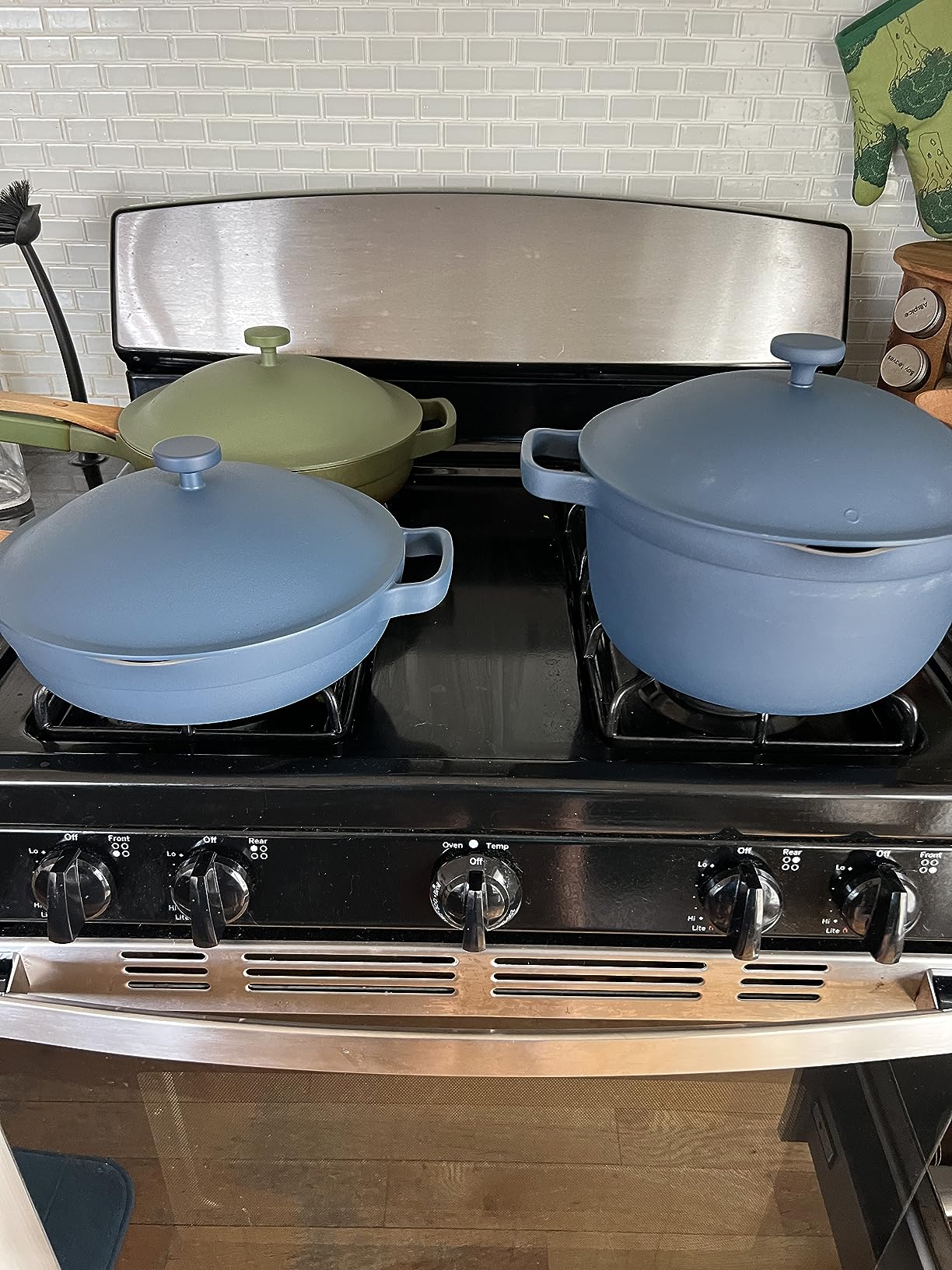 Our Place Always Pan on a kitchen stovetop with steamer basket and wooden spatula