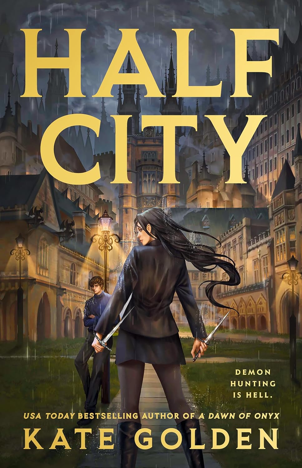 Cover for the urban fantasy novel Half City by Kate Golden. A light-skinned young woman with dark hair is shown from behind as she looks over her left shoulder, a dagger wielded point-up in each hand. On the edge of the path before her, a light-skinned man with brown hair stands leaning against a lamppost, his arms crossed. Behind him is an academy campus with tall towers and pointed roofs, and the sky overhead is dark, gloomy, and rainy.