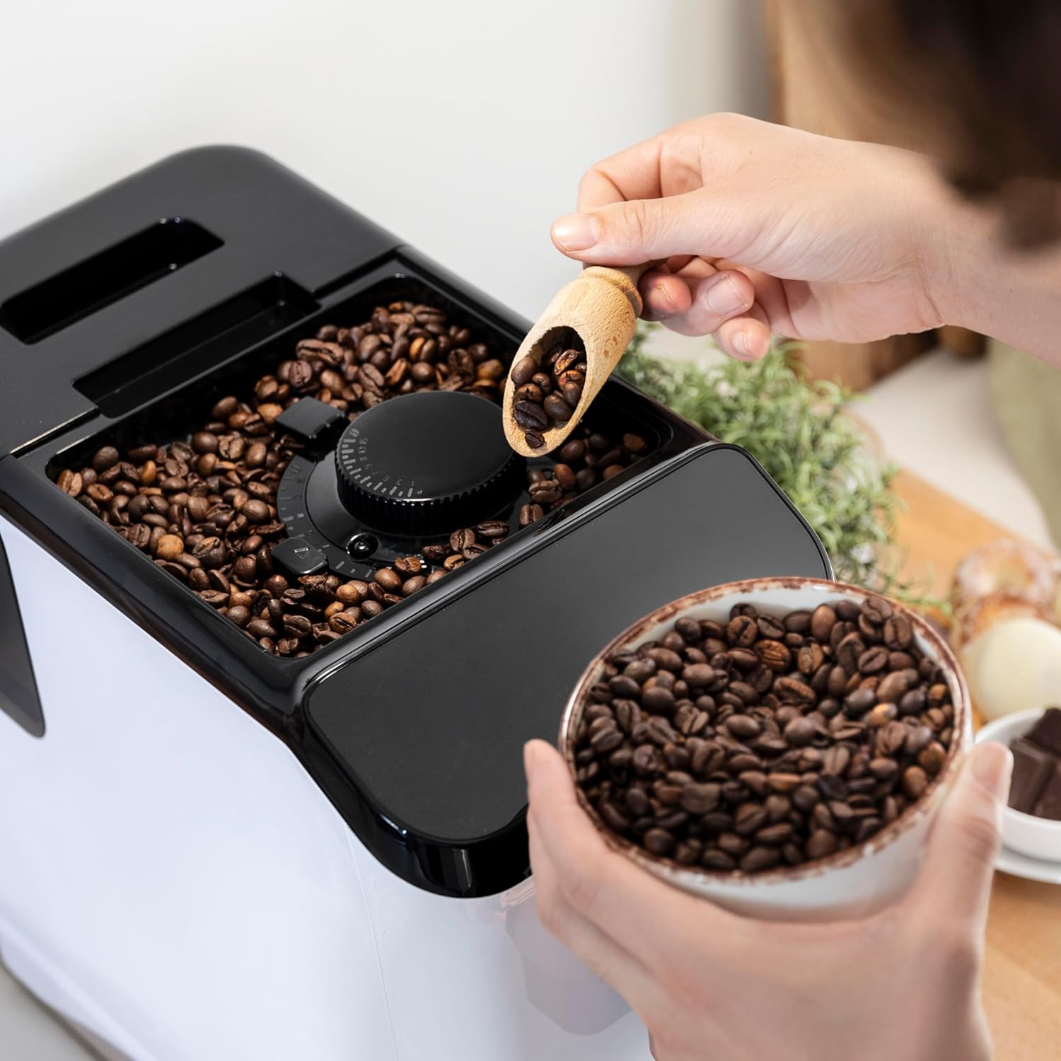 Mani che aggiungono chicchi di caffè al macinacaffè integrato della macchina da caffè Cecotec