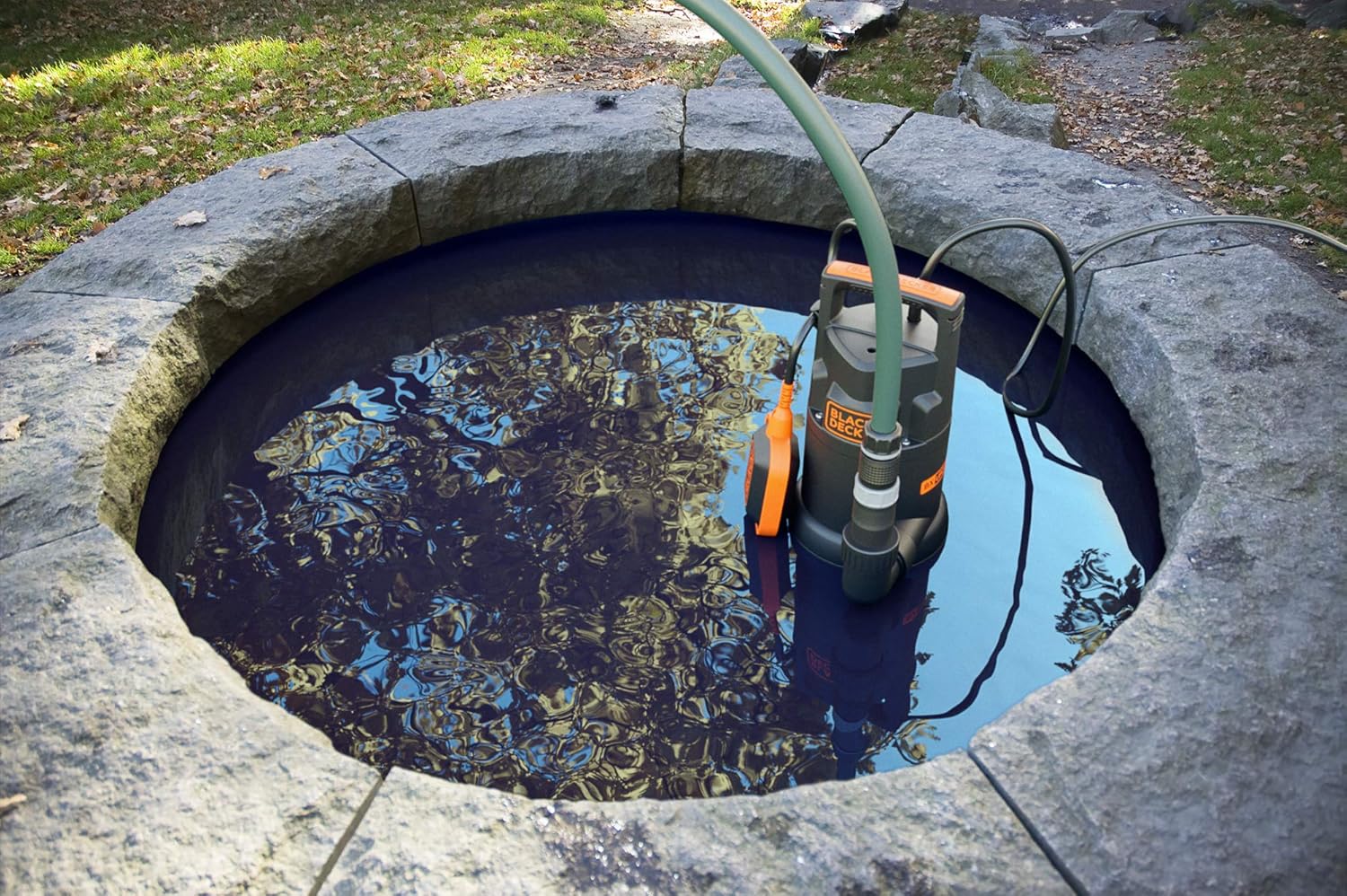 BLACK+DECKER BXUP250PCE submersible pump draining water from a stone well.