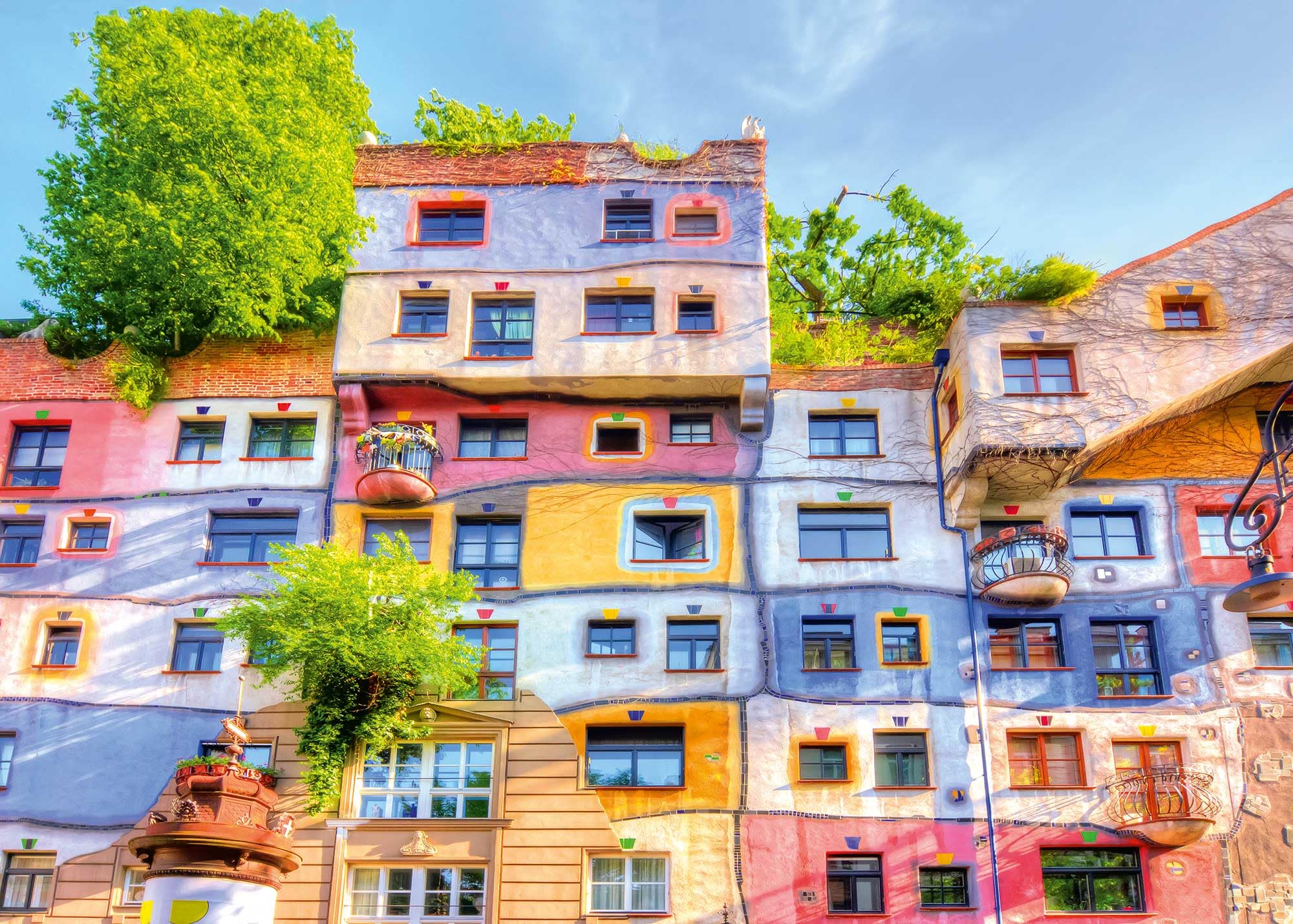 Ulmer Puzzleschmiede - Puzzle « Hundertwasser » – 2000 pièces – La maison colorée de l'artiste Friedensreich Hundertwasser à Vienne, Autriche en forme de puzzle coloré