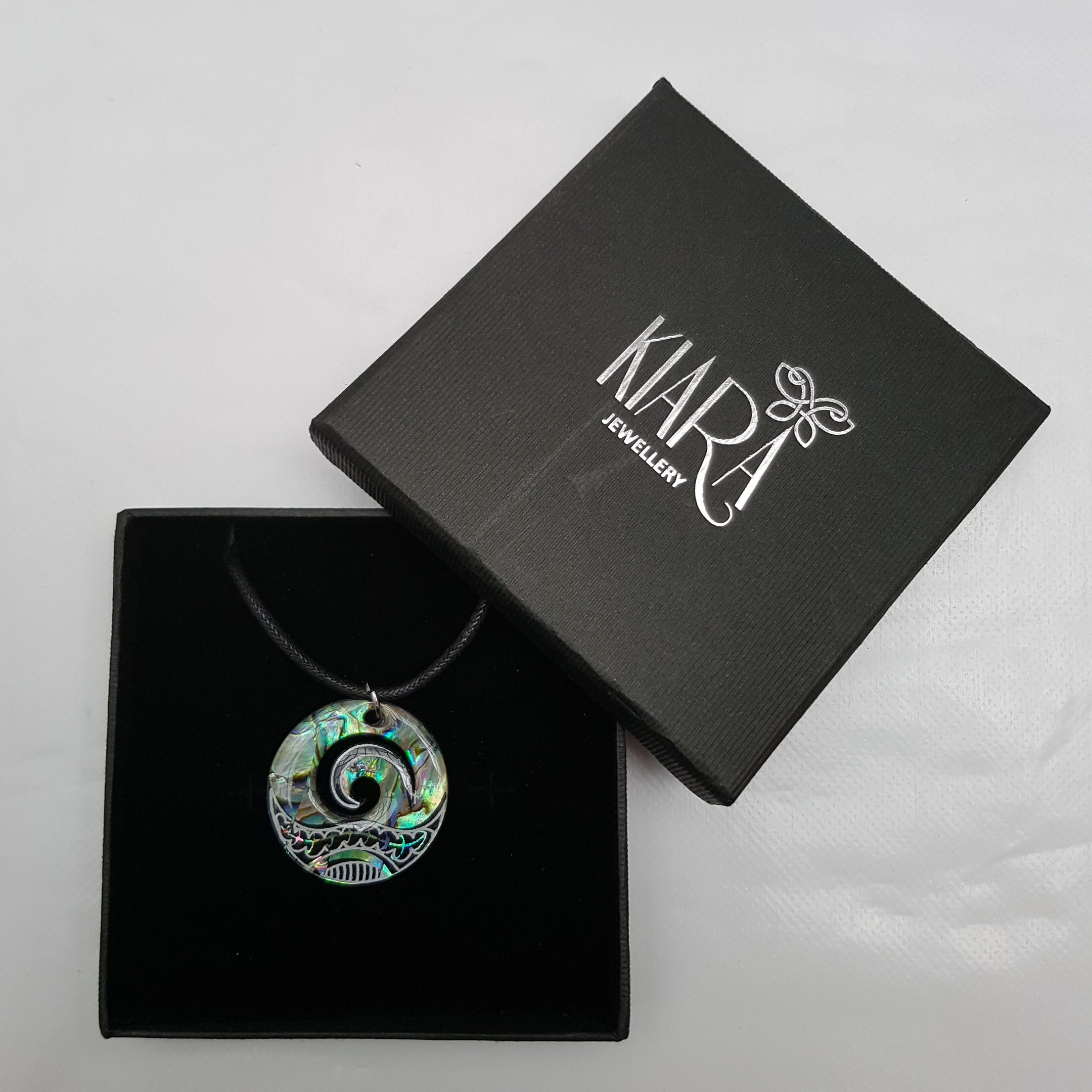 Collier à pendentif Maori Koru ou Wave Crest - Incrustation d'ormeau paua bleuté et vert sur disque en plastique noir - Avec cordon noir de 45,7 cm