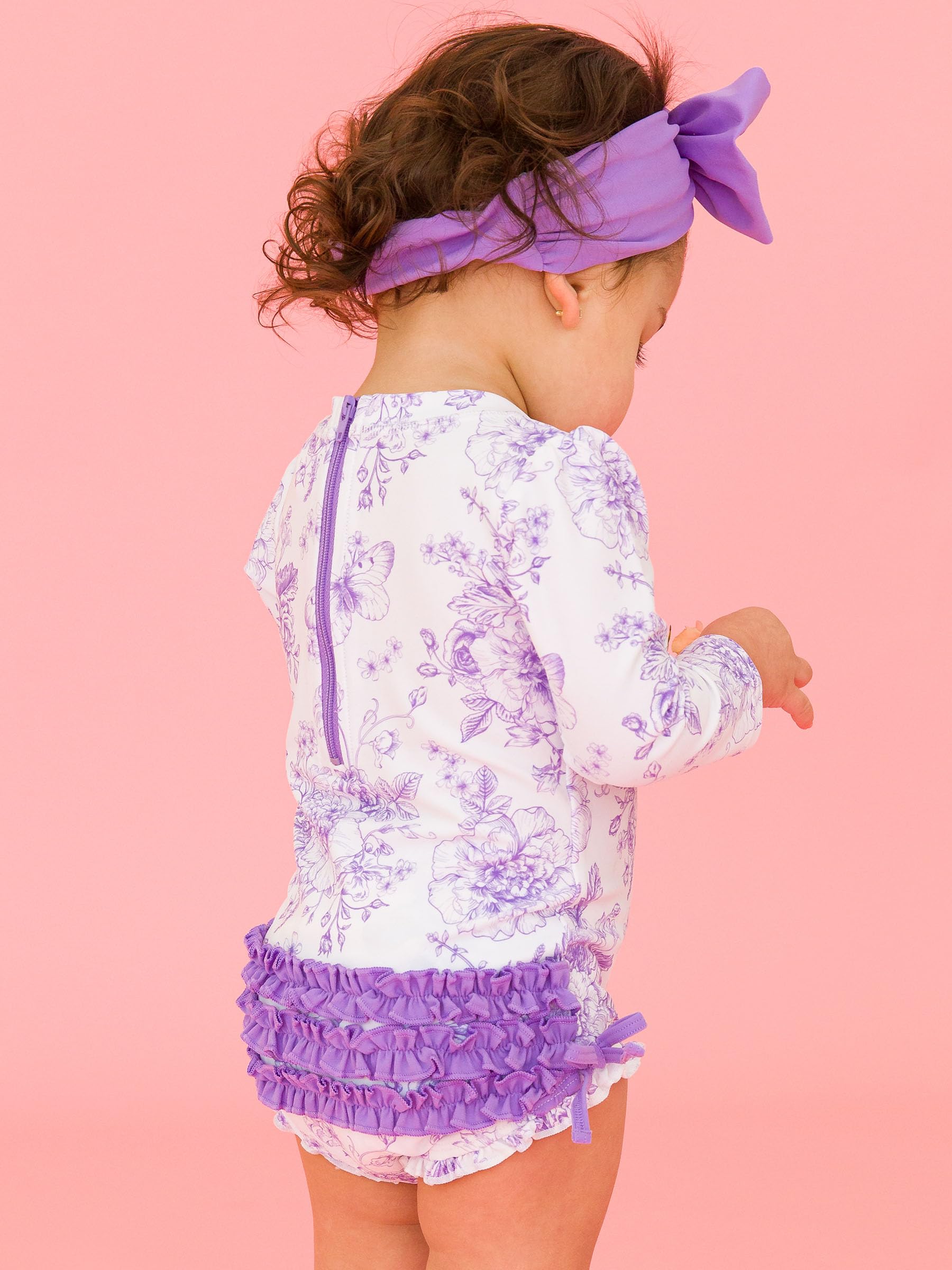 RuffleButts Costume da Bagno Intero A Maniche Lunghe con Stampa Floreale E Protezione Solare UPF 50 per Bambine, con Cerniera, Motivo Giardino di Farfalle Viola Glicine, 18-24 Mesi
