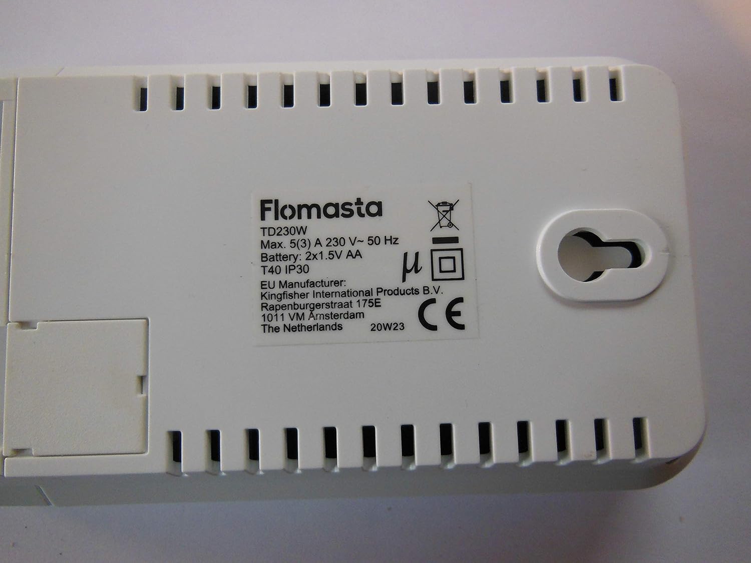 Spate view of the FLOMASTA TD230W thermostat, showing the product label with model number TD230W, electrical specifications (Max. 5(3) A 230 V~ 50 Hz), battery compartment (2x1.5V AA), IP30 rating, and manufacturer details.