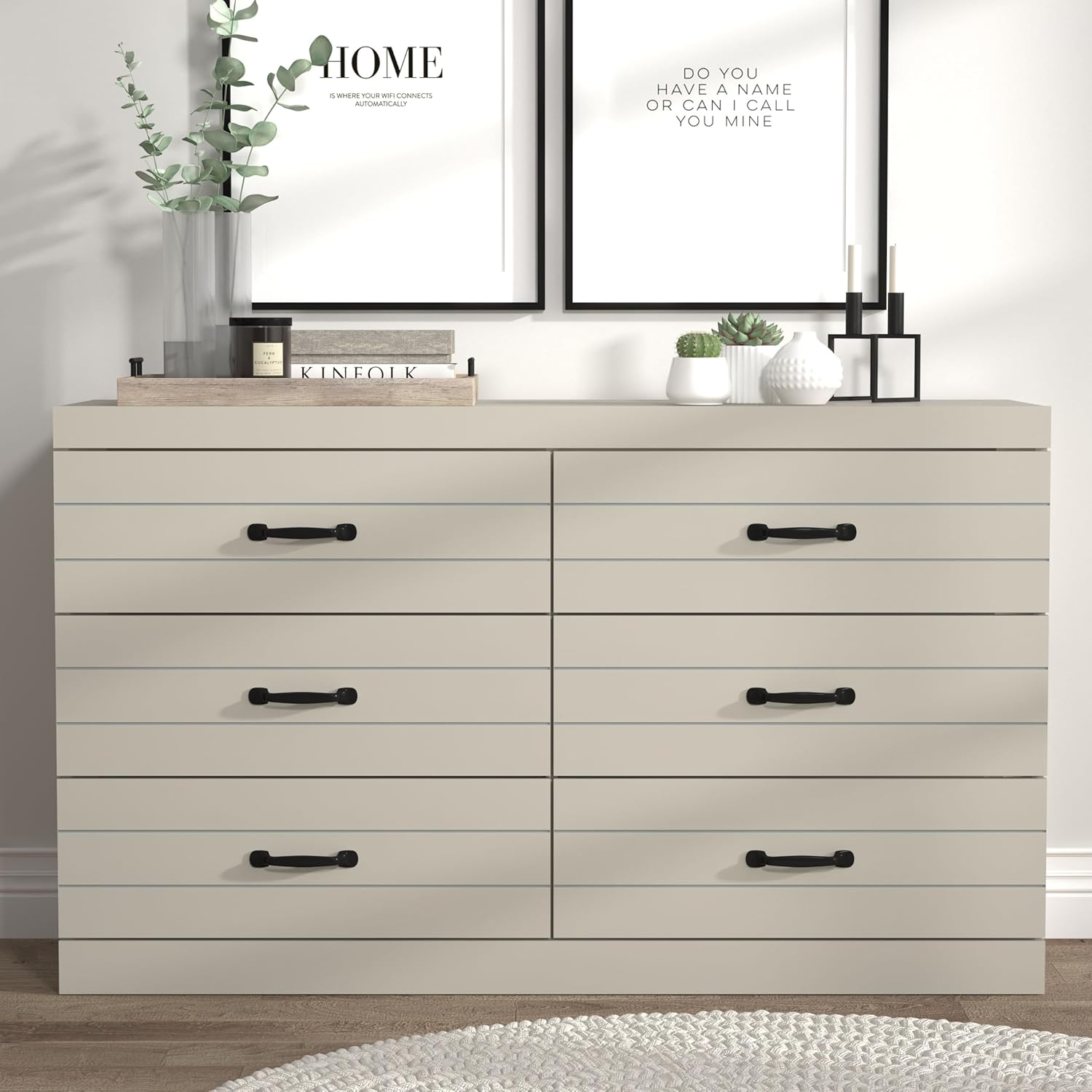 The Galano Milton 6-Drawer Dresser in a light grey finish, featuring six drawers with black handles, styled in a modern room.