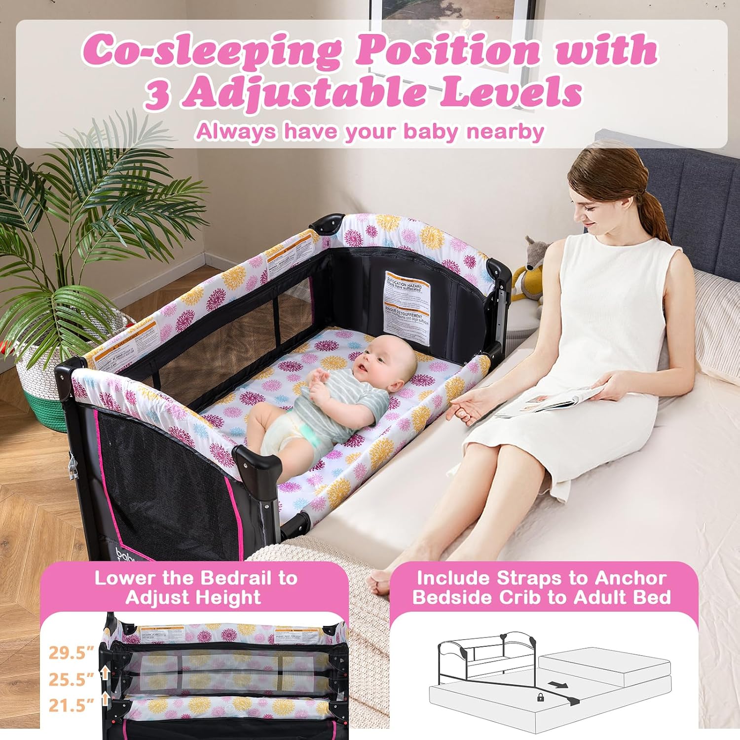 Mother sitting on a bed next to the BABY JOY Pack and Play in bedside sleeper mode, showing the adjustable height feature and safety strap for anchoring to the adult bed.
