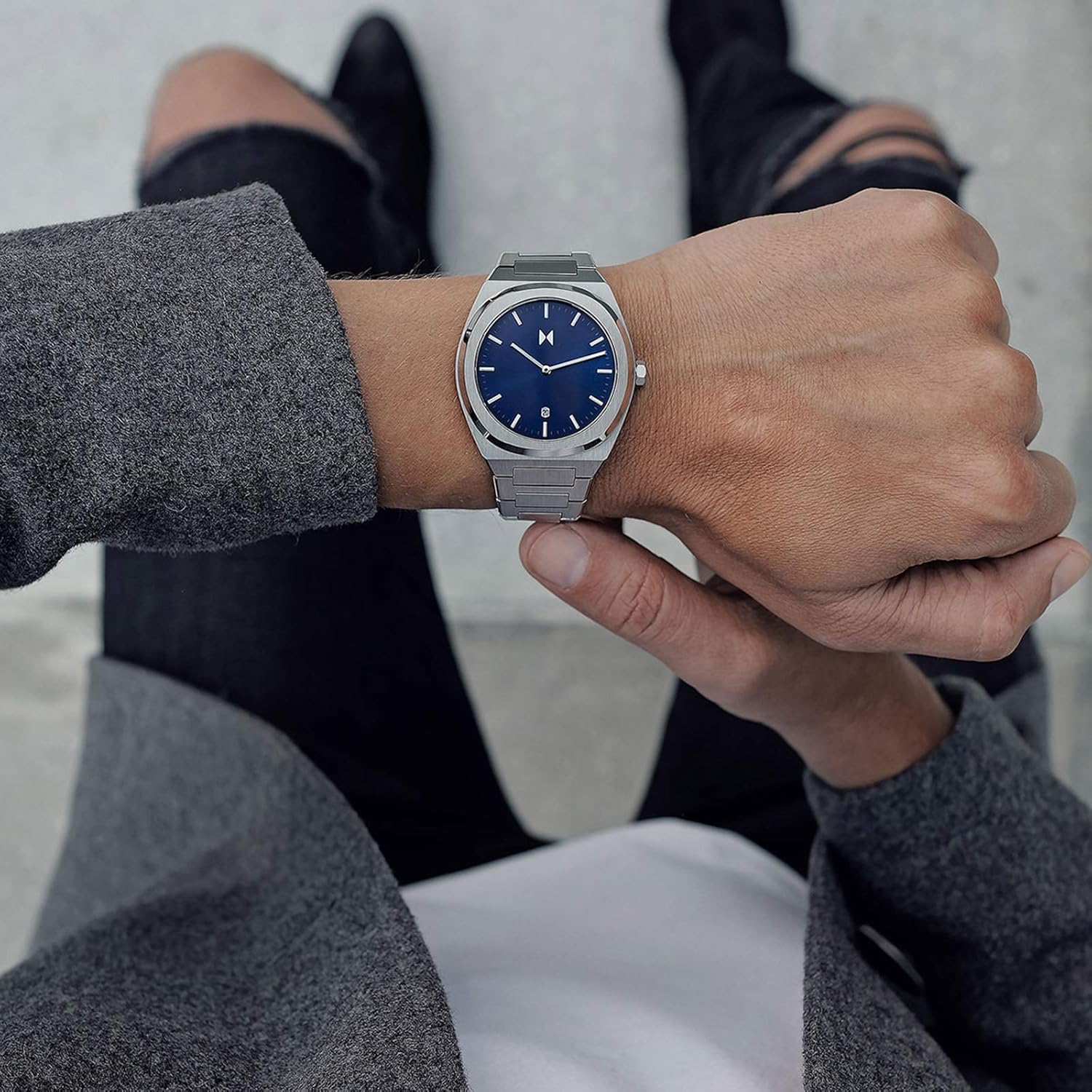MVMT Odyssey Axiom watch on a man's wrist, viewed from above, with a casual outfit.