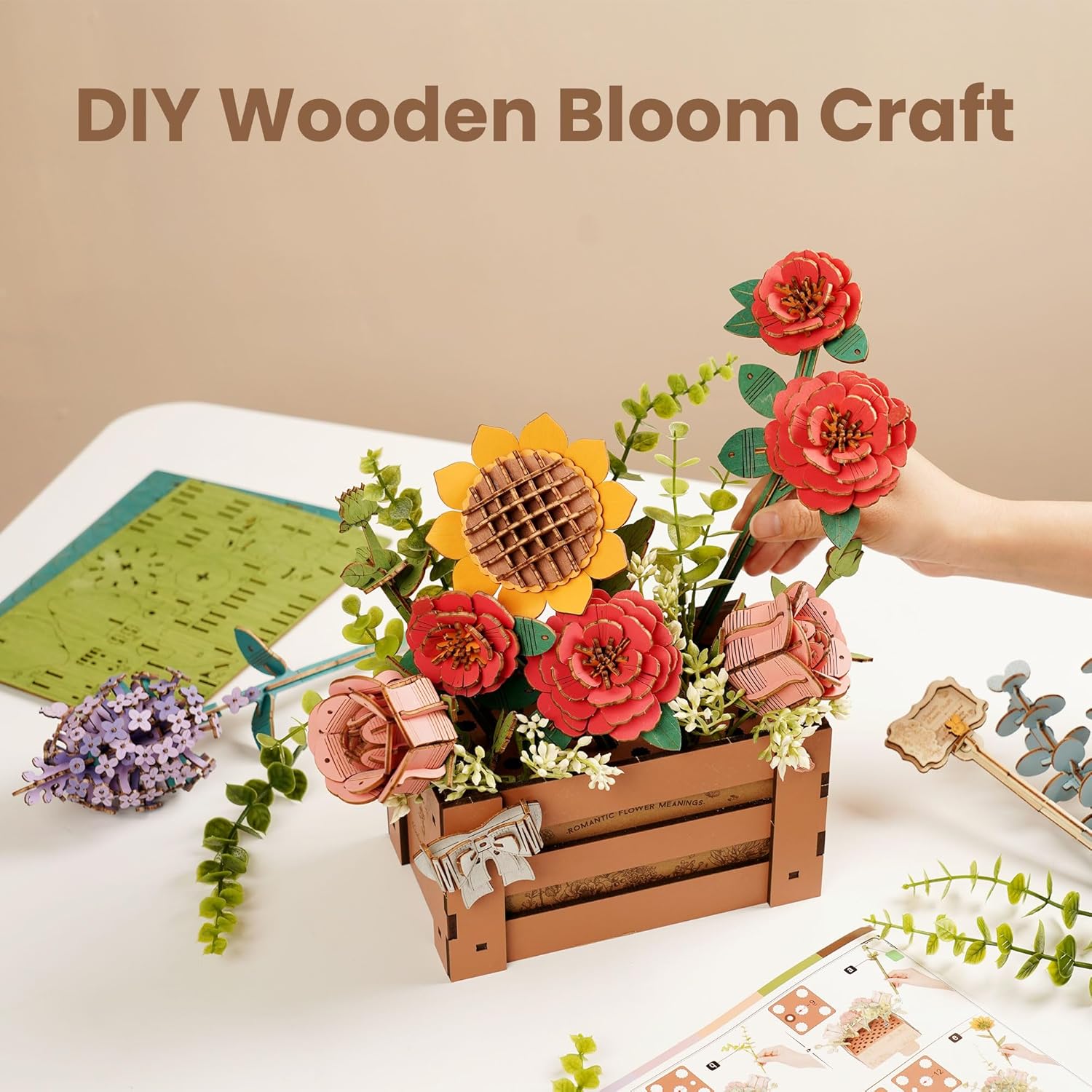 A hand holding an assembled wooden flower, with other components and the instruction manual visible on a table.