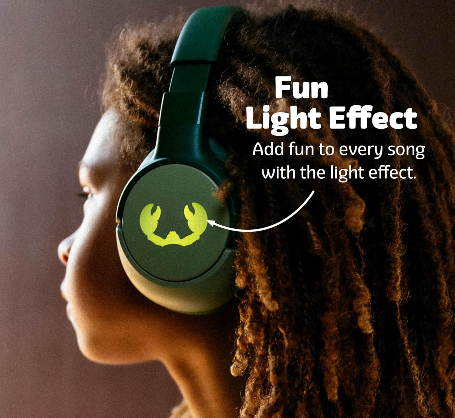 A child wearing green Fresh 'n Rebel Clam Junior headphones, with an arrow pointing to the illuminated crab logo on the earcup, indicating 'Fun Light Effect'.