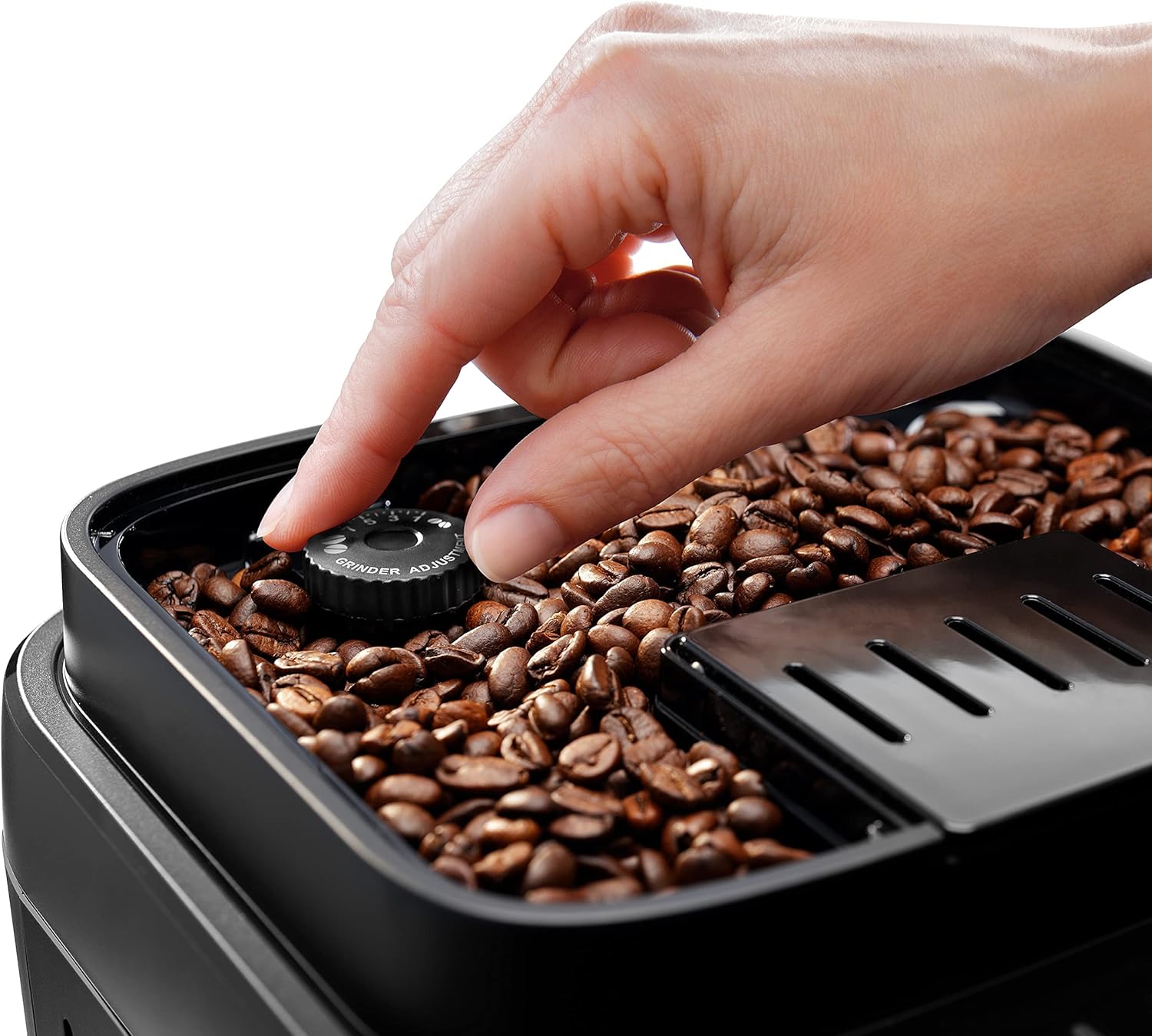 Hand adjusting the grind fineness dial on the De'Longhi Magnifica Evo coffee machine