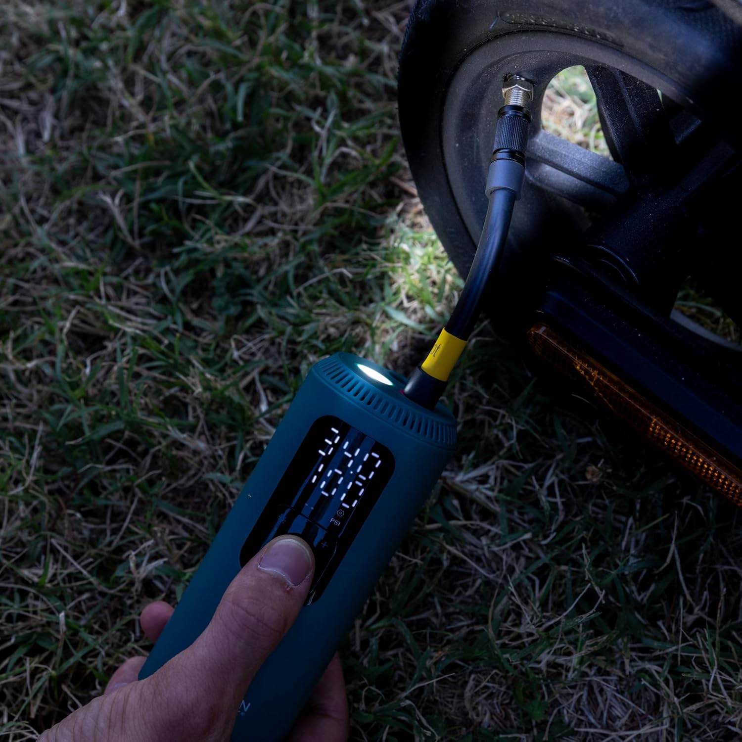 Urban Prime air compressor with LED light on, illuminating a scooter tire valve during inflation
