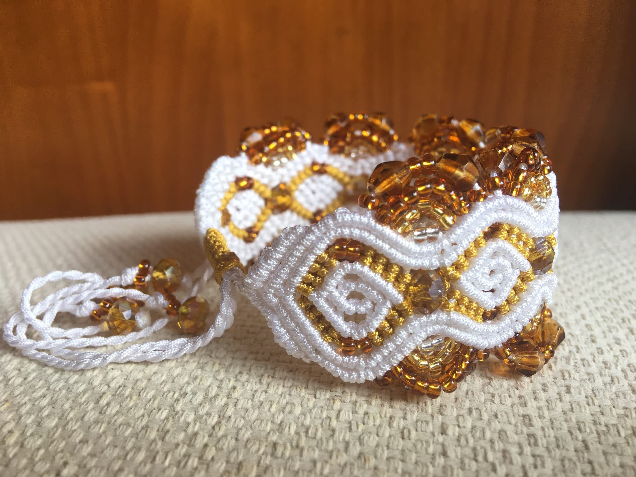 Pulsera macramé blanca y oro artesanal con cuentas cristal en tono ámbar en degradé, cierre ajustable