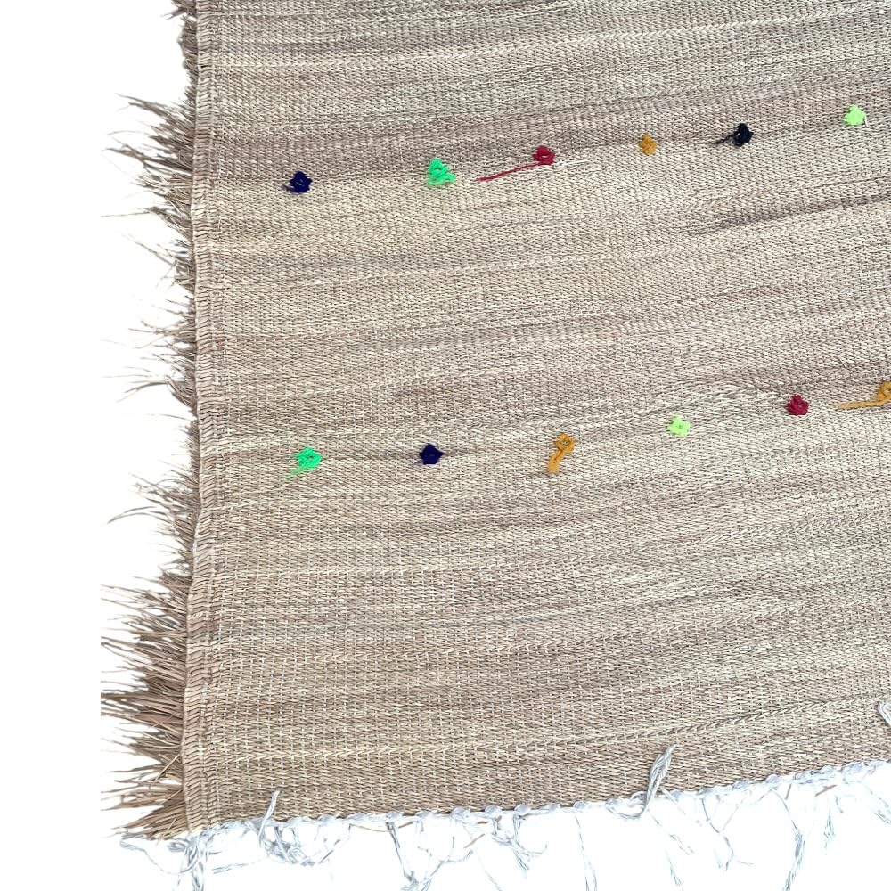 Tapis Hassira marocain en paille de palmier tissée à la main par des artisans experts du Maroc. Complétez le tapis des broderies berbères simples en laine colorée naturellement.