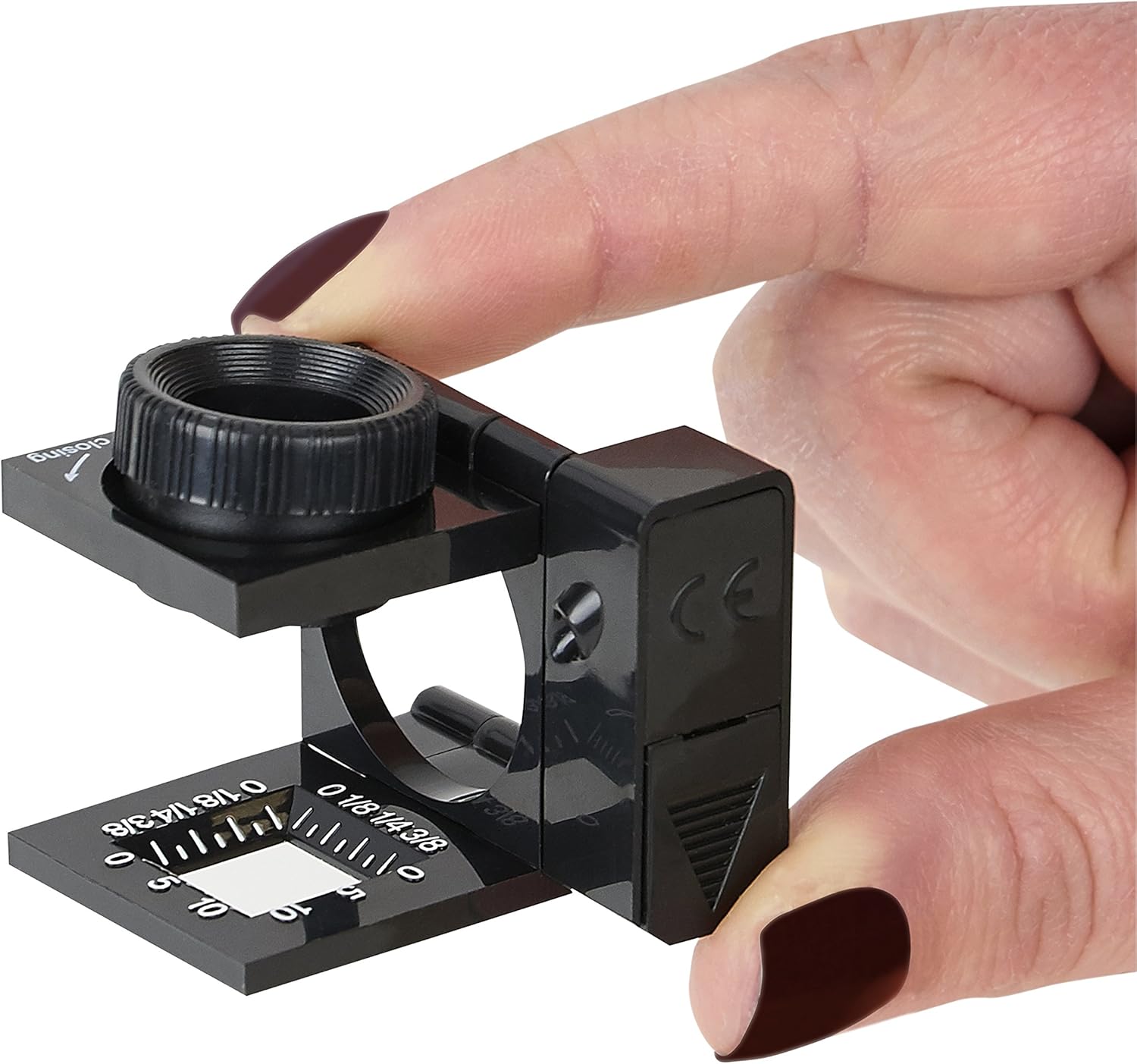 A hand holding the Carson LT-10 loupe in an unfolded position, demonstrating how to operate the light switch.