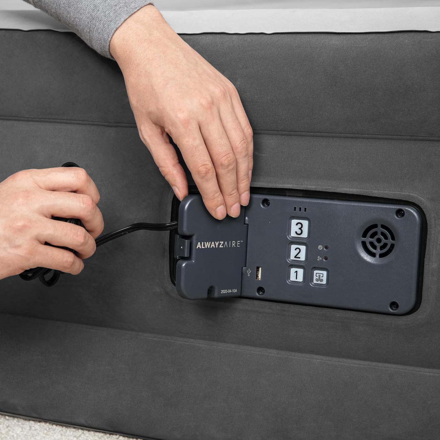 Hands plugging the power cord into the built-in pump of the airbed.