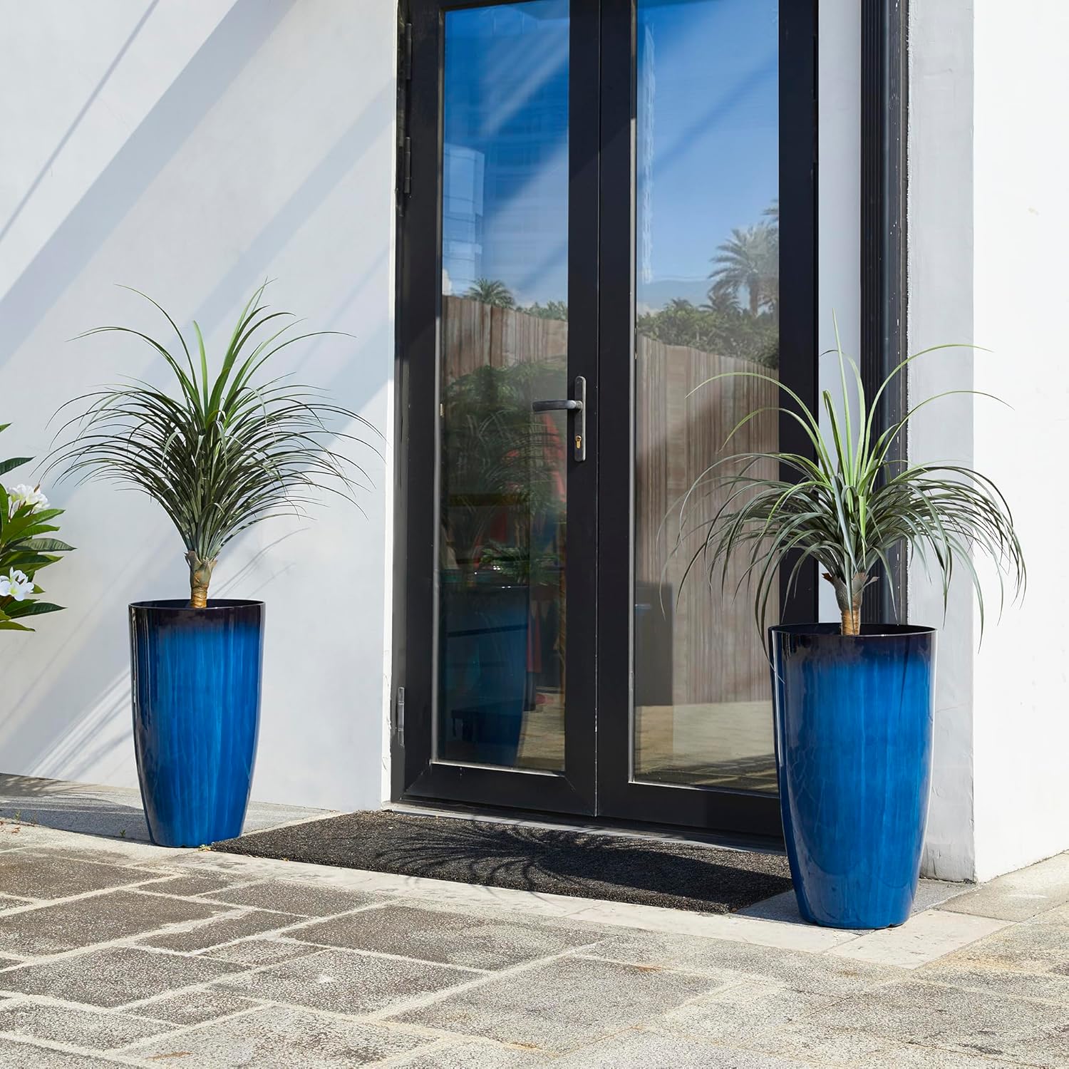 Two Glitzhome planters with plants positioned indoors next to a sofa, showcasing their suitability for interior decor.