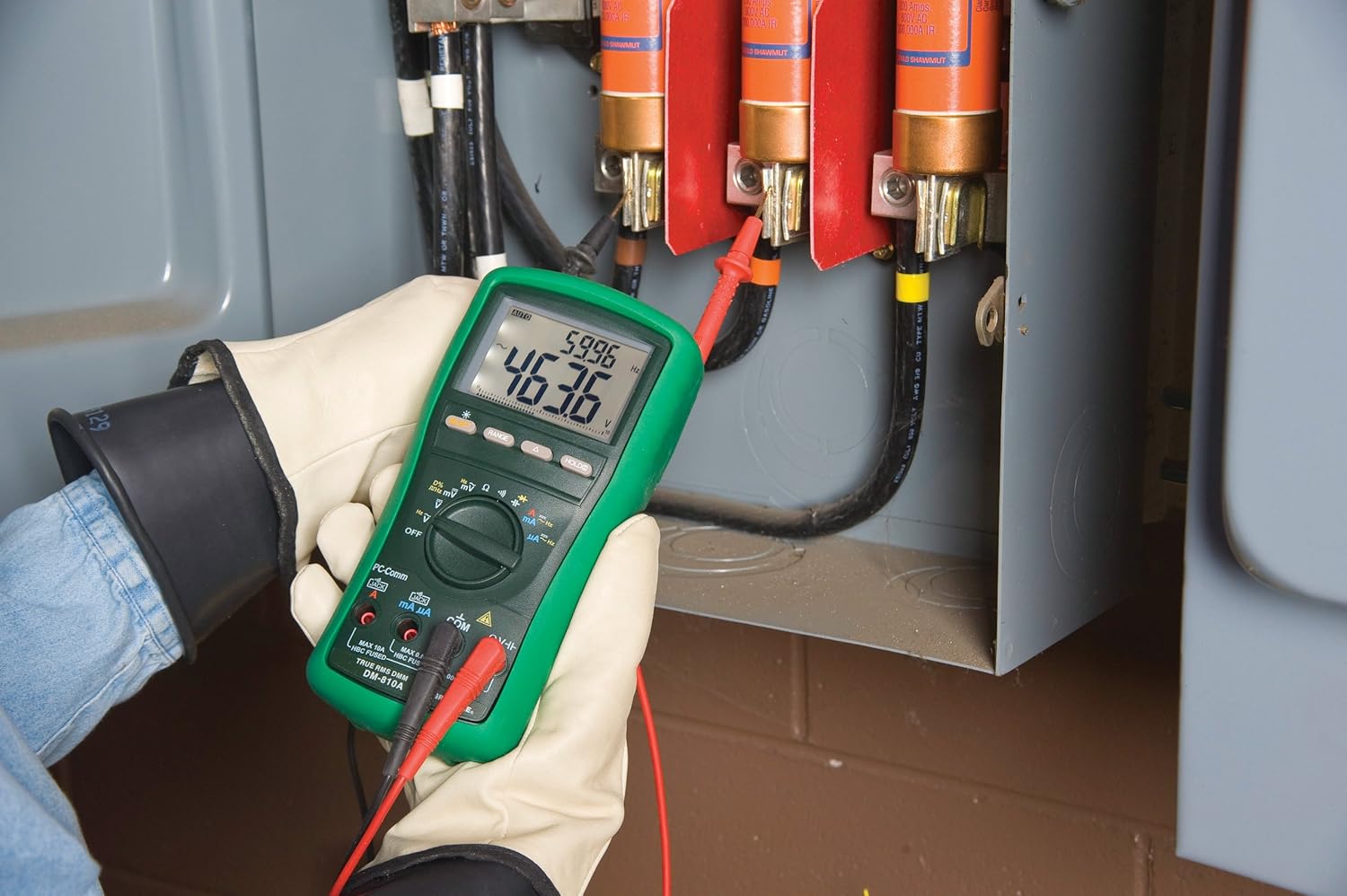 Greenlee DM-810A Digital Multimeter in use, measuring an electrical panel