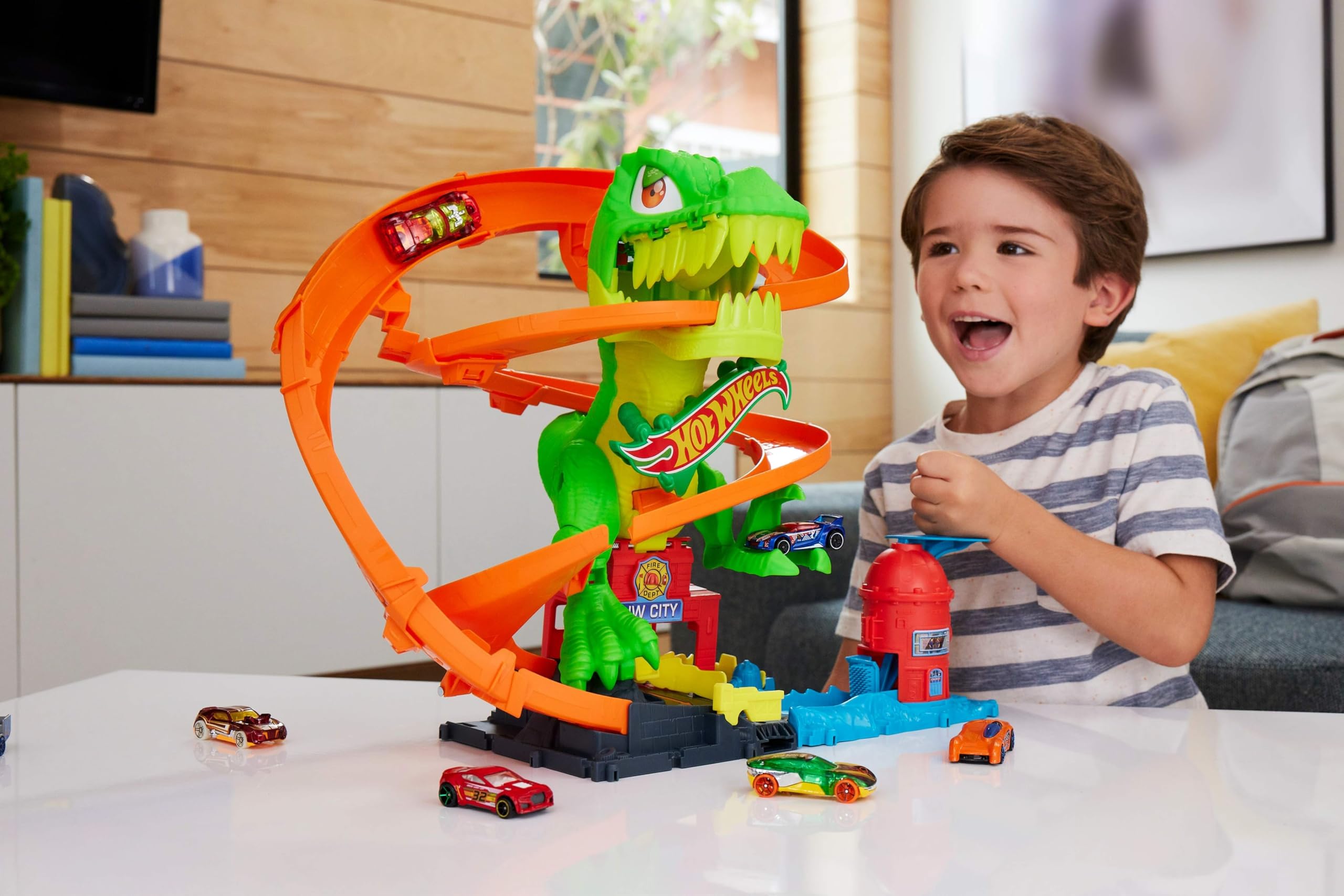 Hot Wheels City - T-Rex Battaglia Infuocata, playset stazione dei pompieri con dinosauro occhi rotanti e pista per gareggiare, camion dei pompieri incluso, giocattolo per bambini, 4+ anni, JBM73