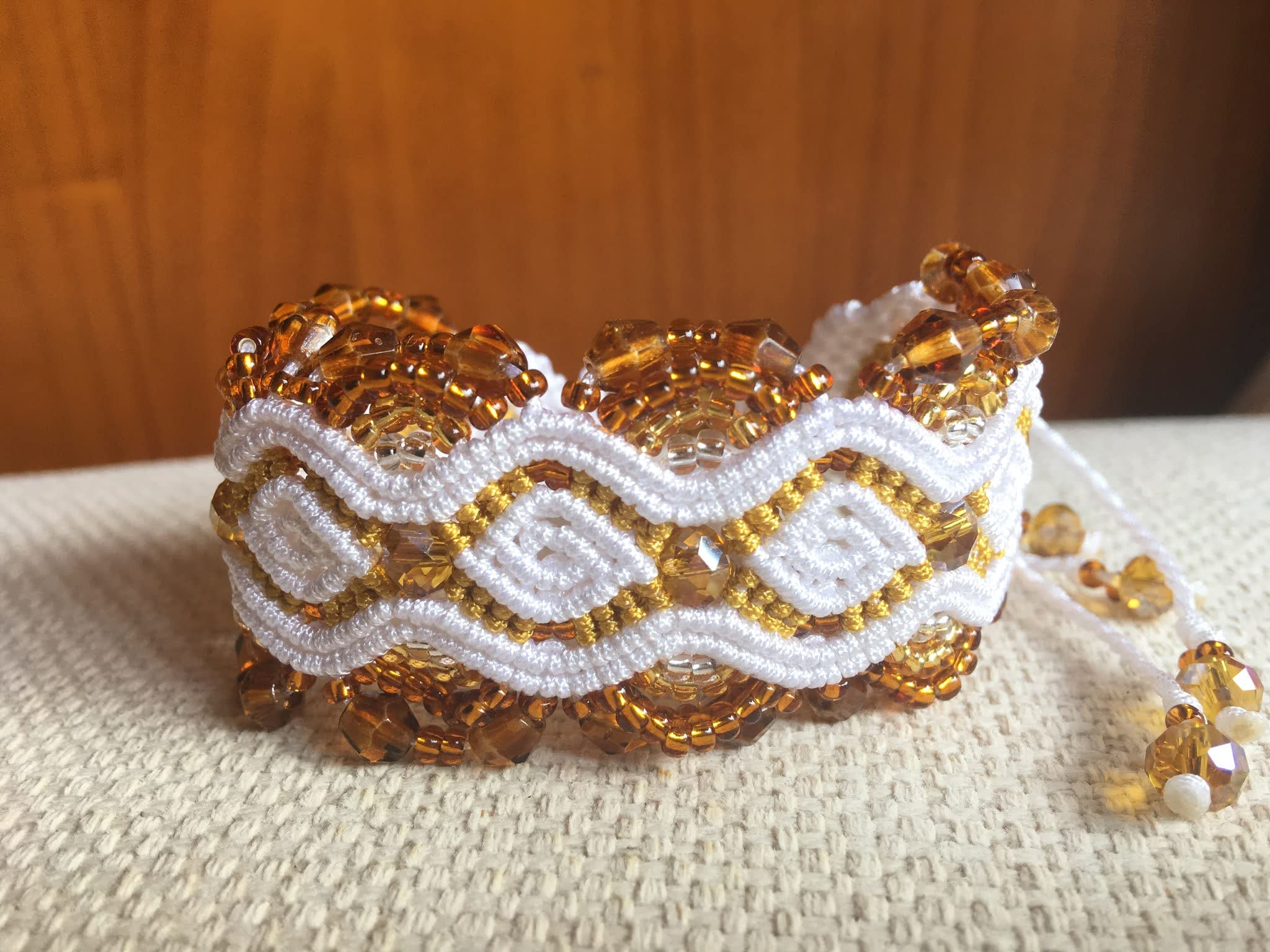 Pulsera macramé blanca y oro artesanal con cuentas cristal en tono ámbar en degradé, cierre ajustable