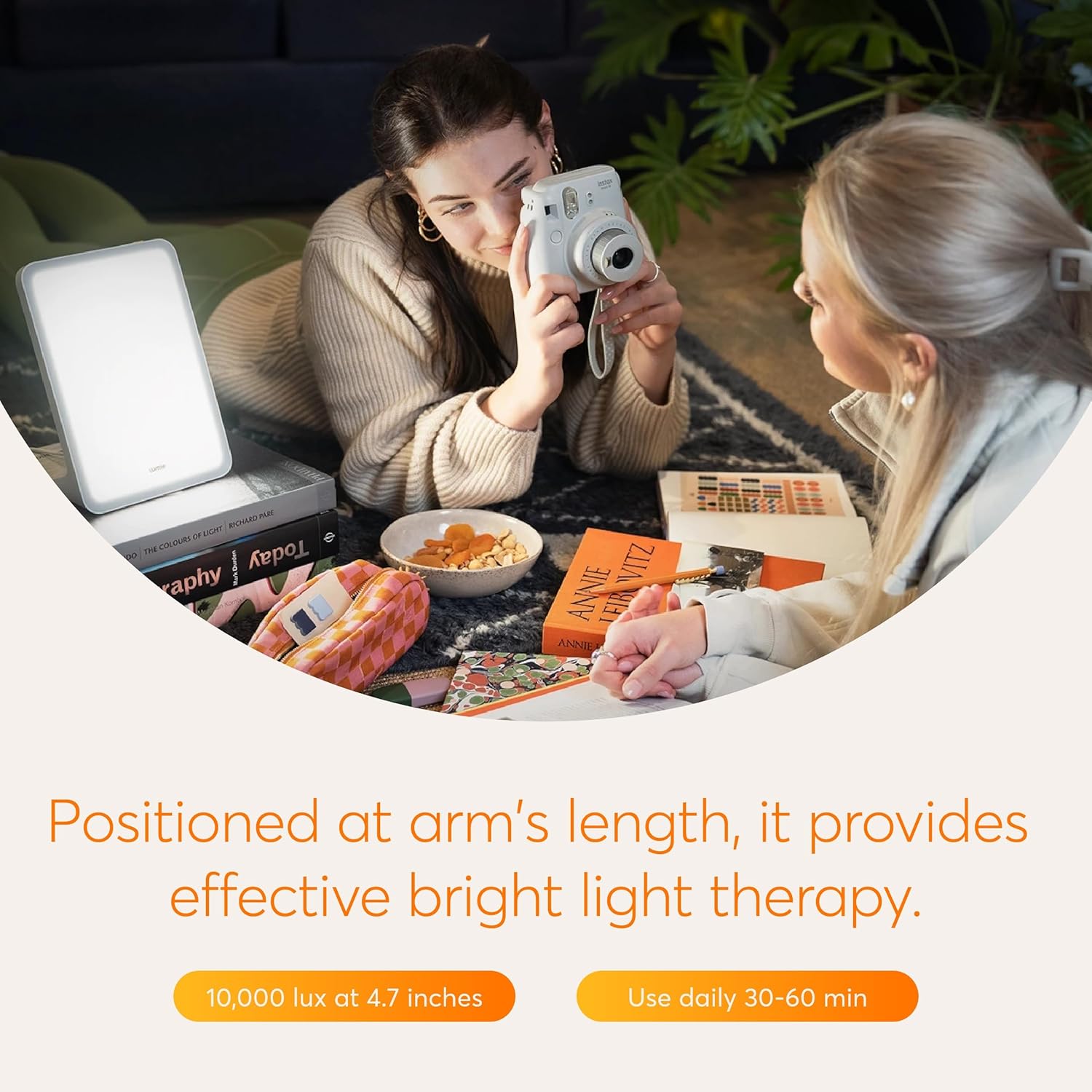 A person is shown reading a book with the Lumie Mini Lamp positioned nearby, highlighting its use during daily activities to regulate circadian rhythms.