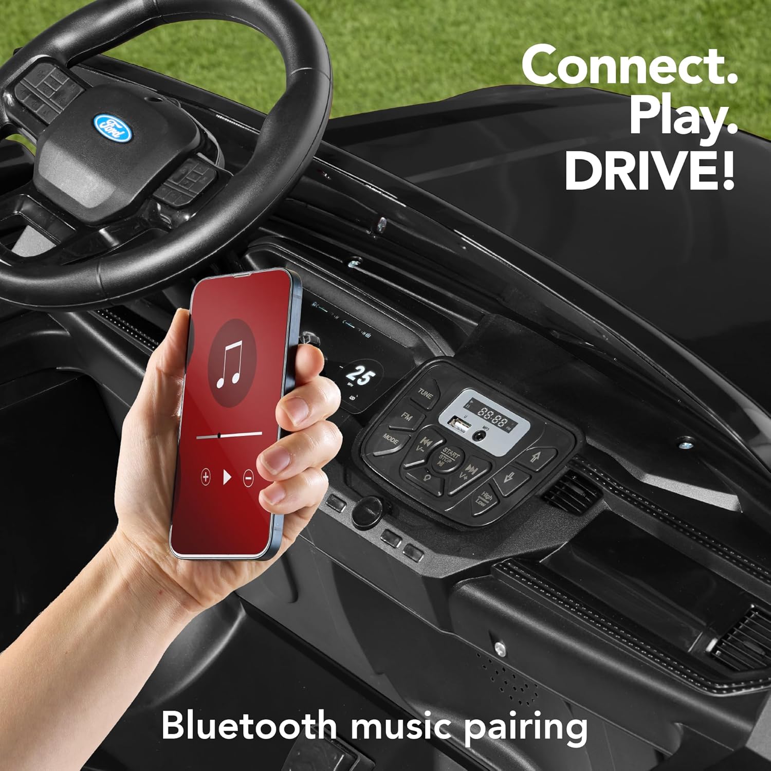 A hand holding a smartphone near the dashboard of the ride-on truck, illustrating the Bluetooth music pairing feature.