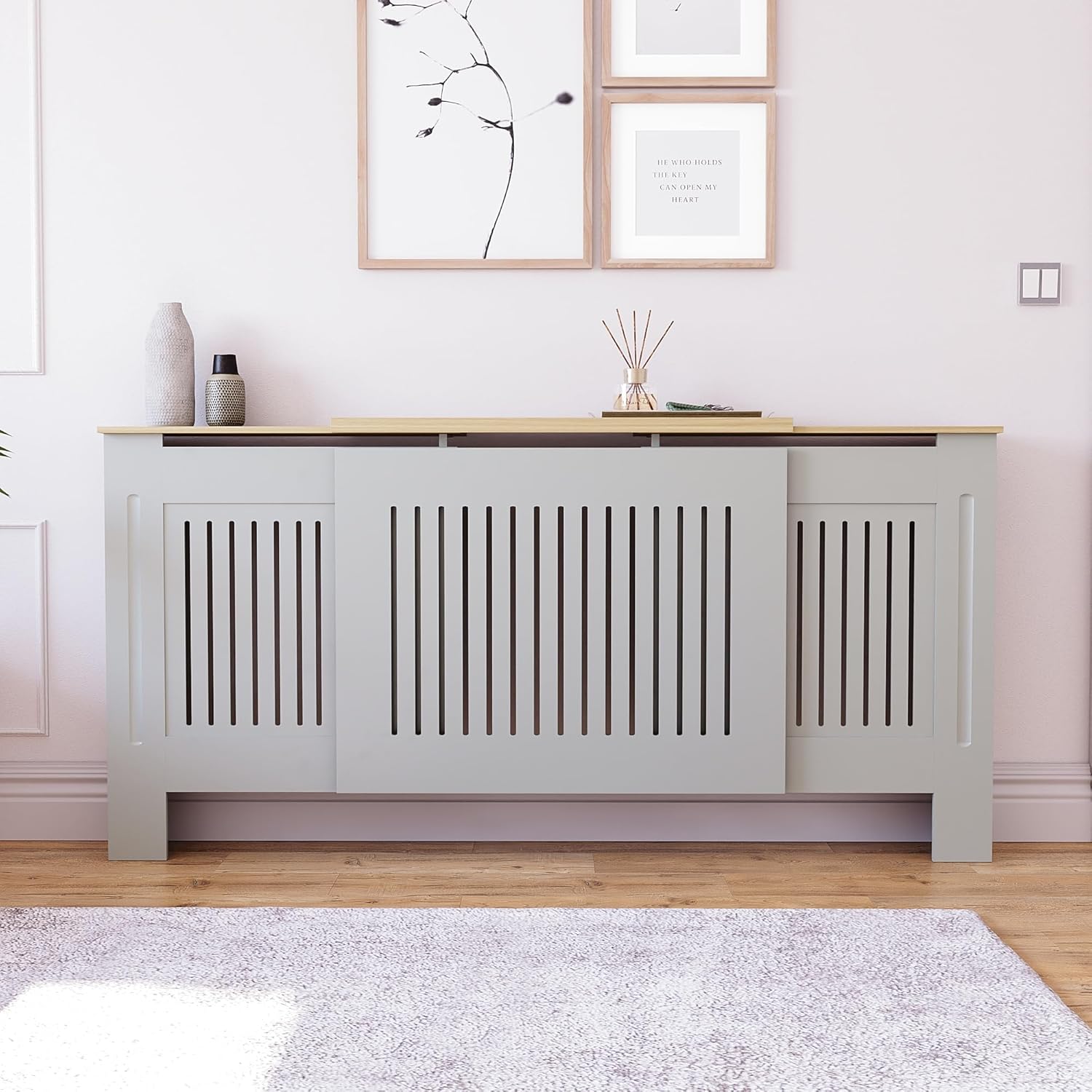 Vida Designs Arlington Adjustable Radiator Cover in grey, installed in a modern living space with decorative items on top.