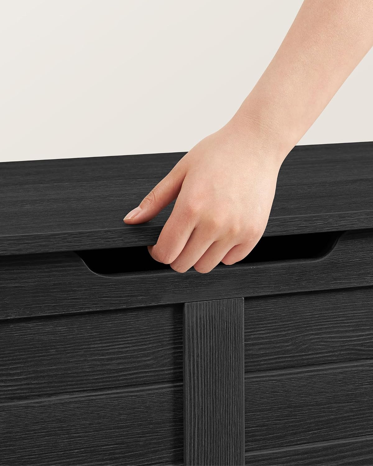 Hand opening the lid of the VASAGLE Storage Bench using the front cutout handle