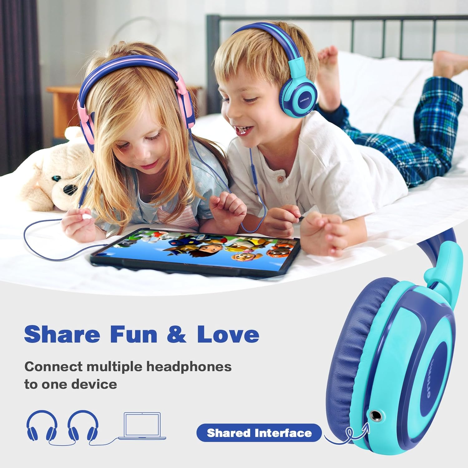 Two children, a boy and a girl, lying on a bed and sharing audio from a tablet using two pairs of SIMOLIO kids headphones connected via the sharing jack.